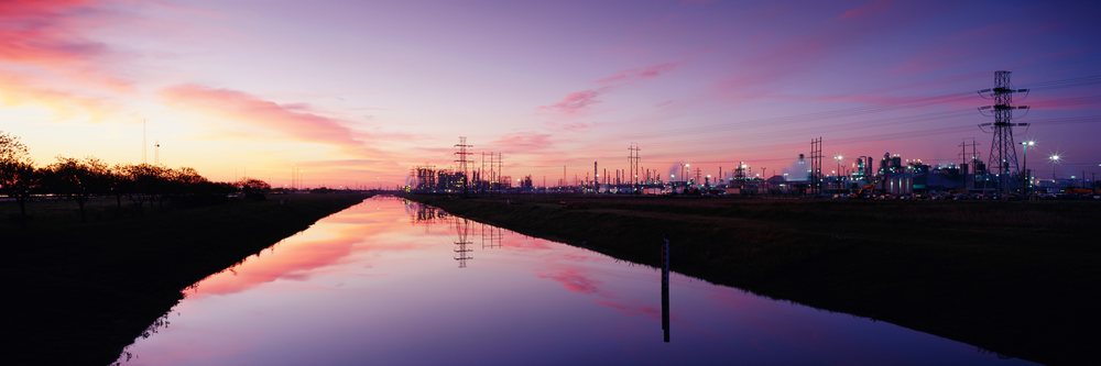 Oil refinery reflecting in canal at sunset