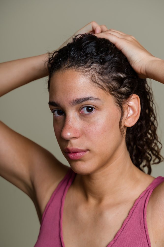 Hispanic woman with curly hair holding hair up portrait