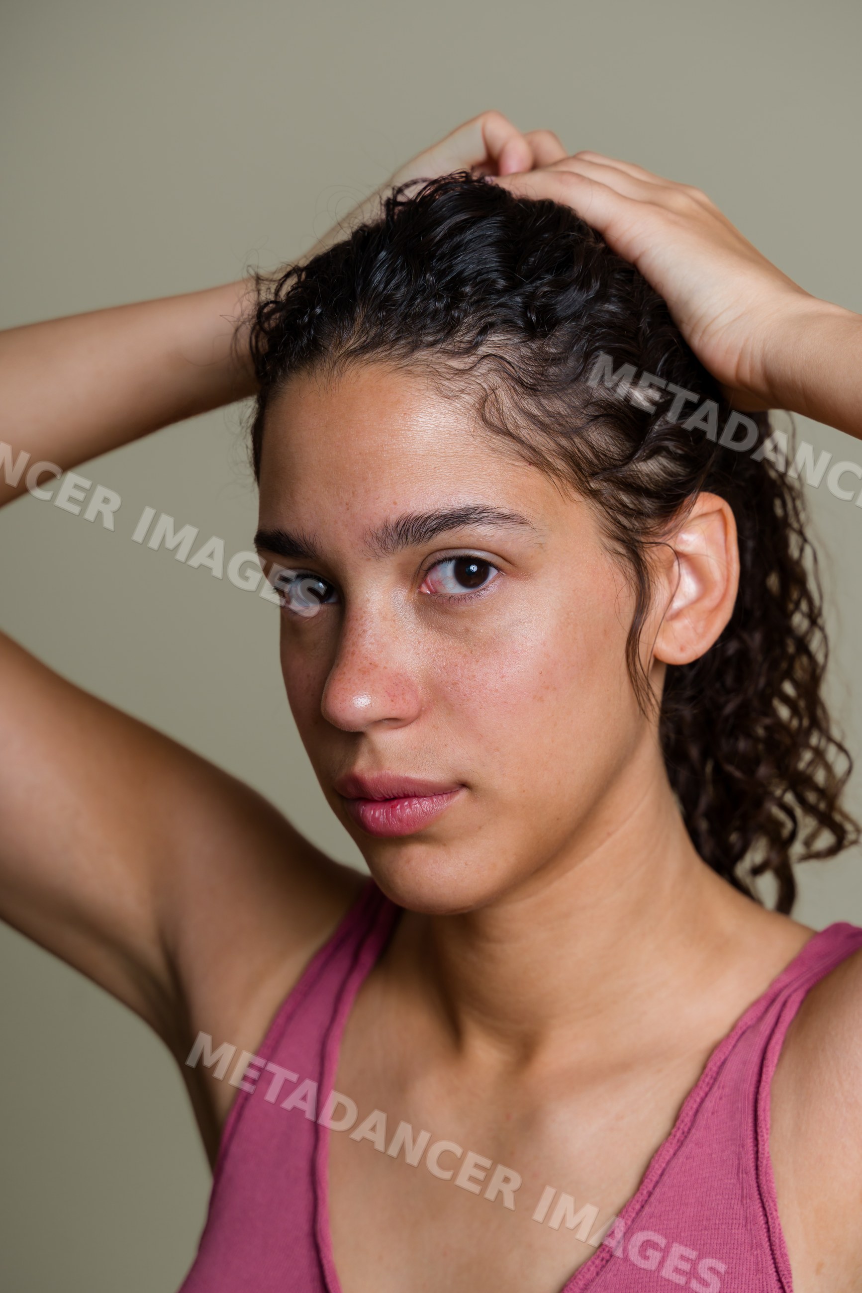 Hispanic woman with curly hair holding hair up portrait