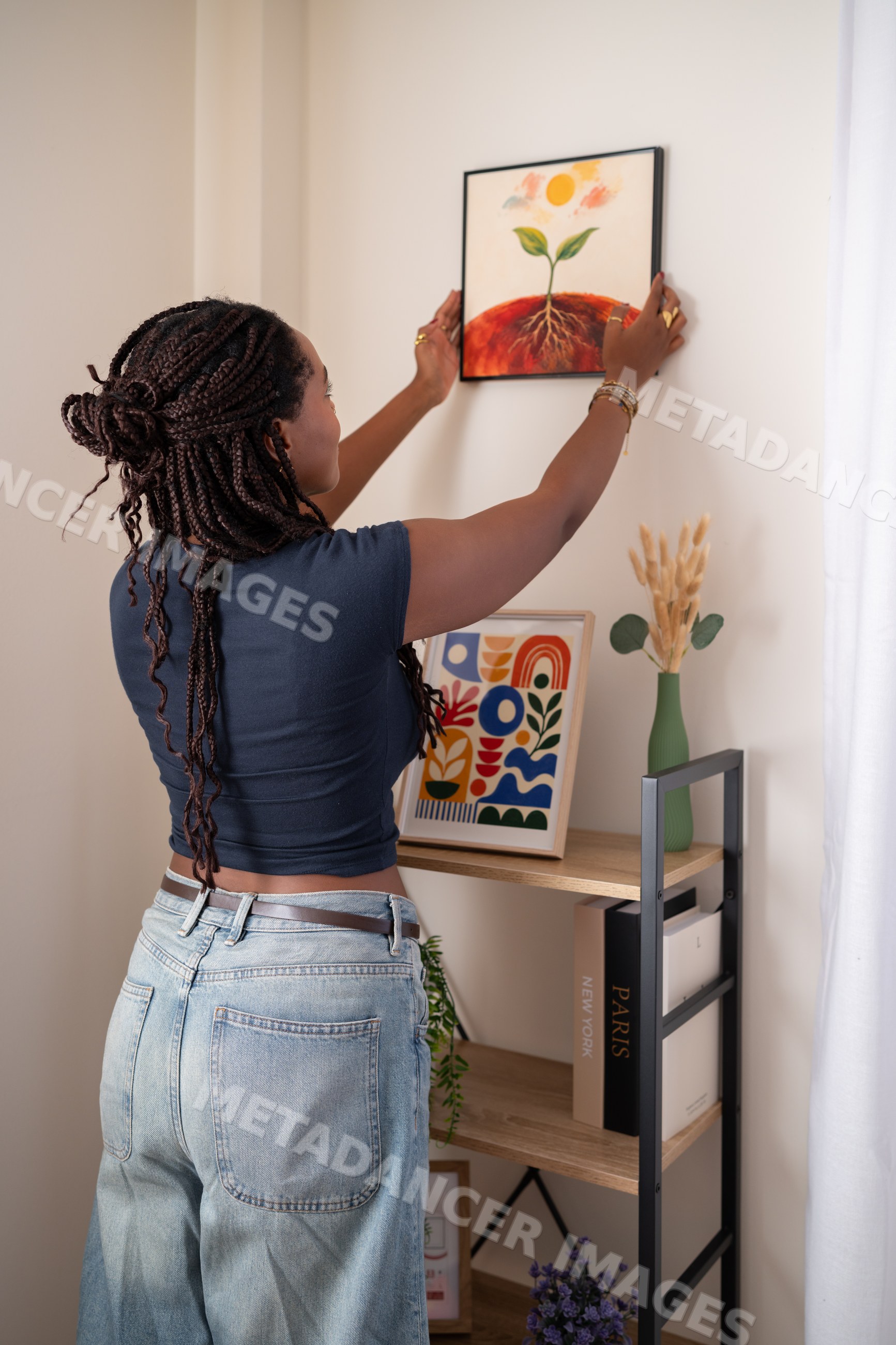 African American woman hangs artwork on a wall