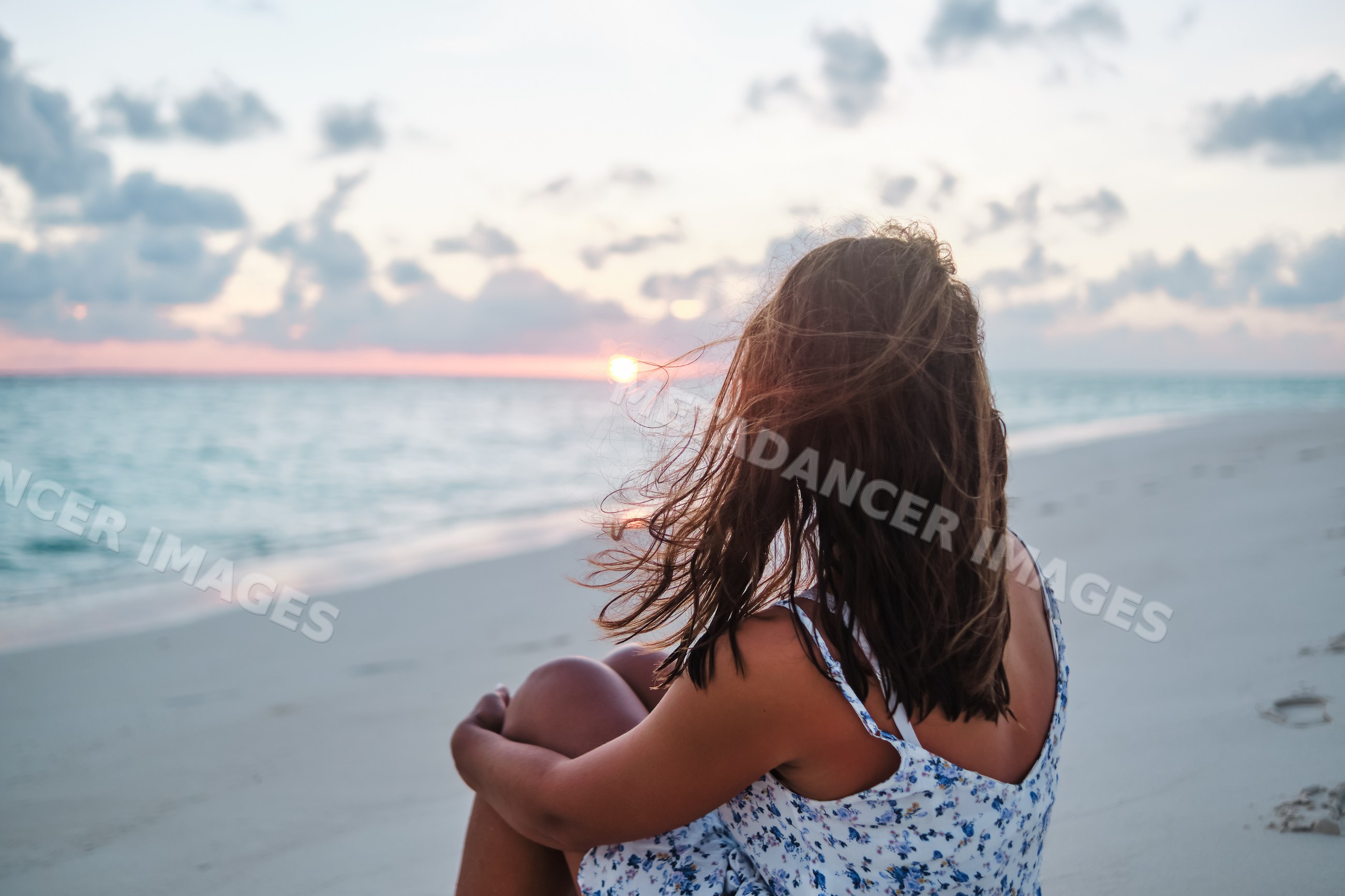 A white woman peacefully sitting on a Maldives beach watching