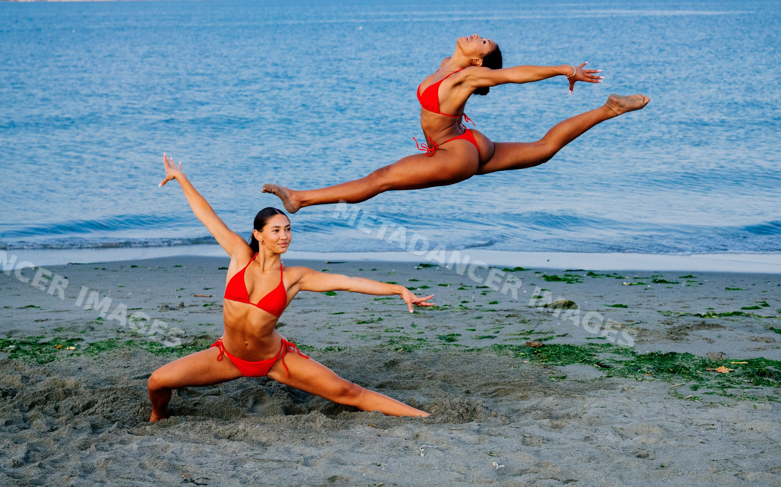 Two women performing partner yoga acrobatics on a beach in wa USA