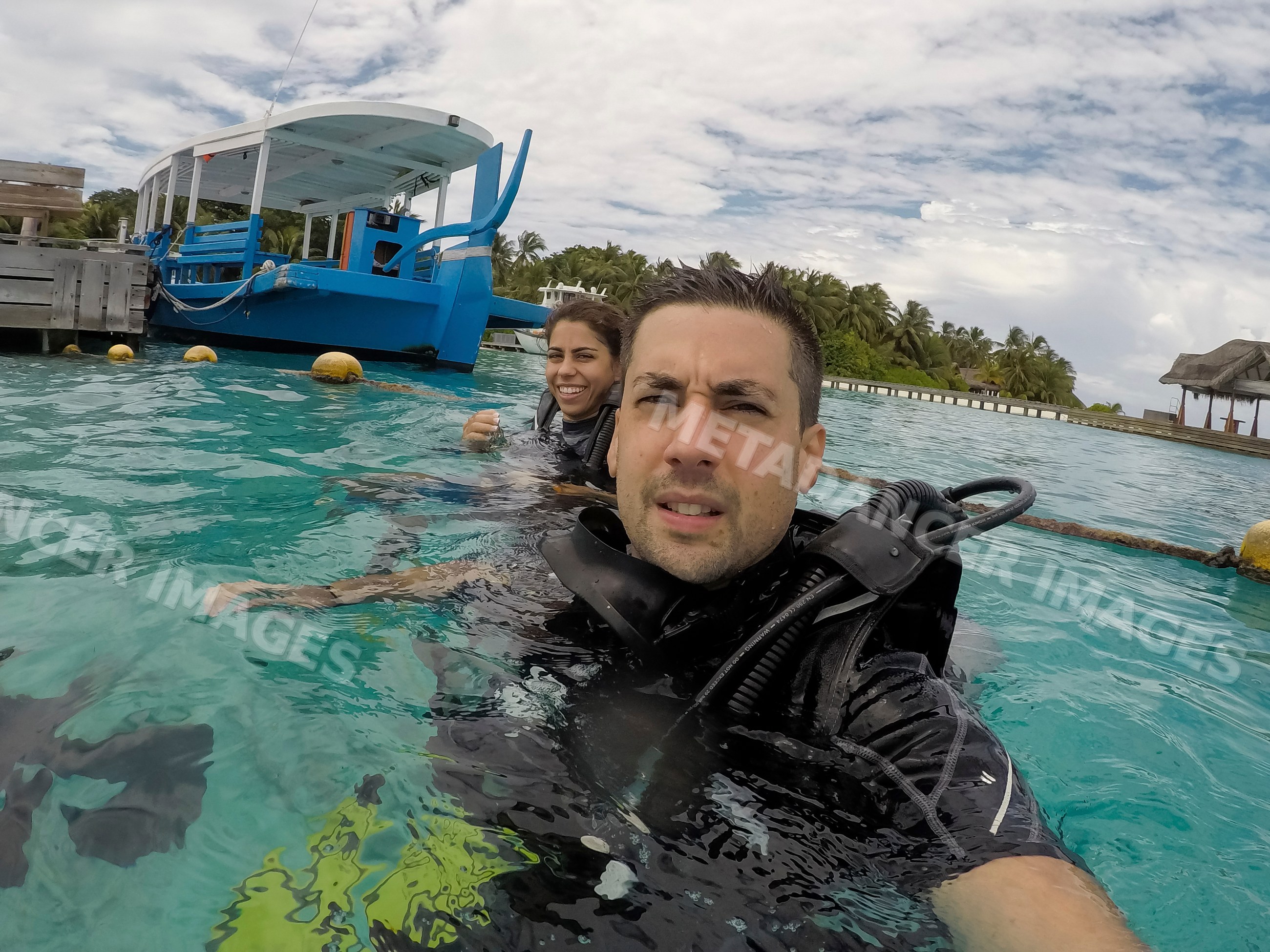 A scuba diving couple enjoys tropical waters near an island resort