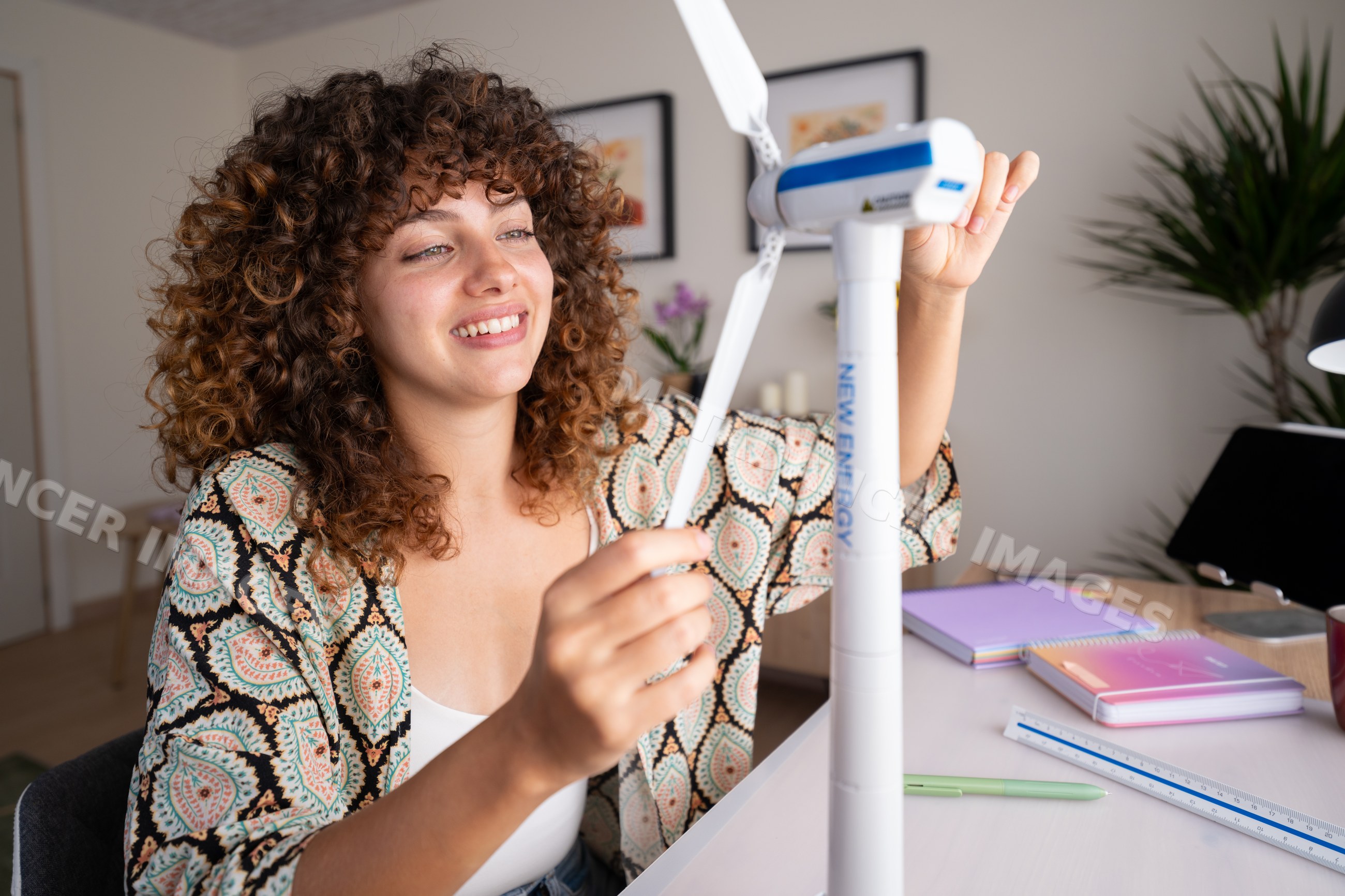 White woman assembling wind turbine model at home desk in Spain