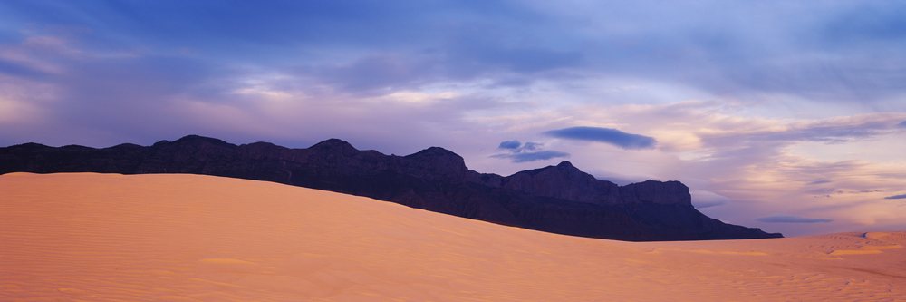Sand dune and mountain range at sunset