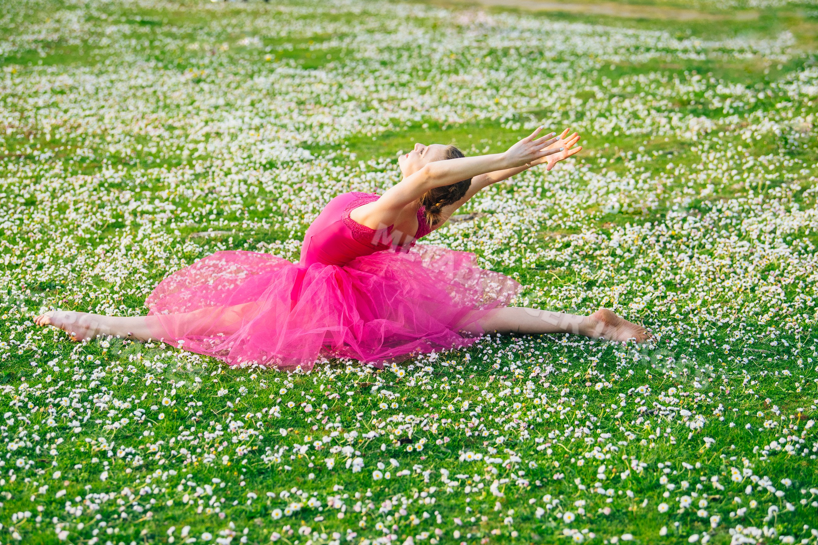 Ballet white dancer stretching in split on daisy field outdoors