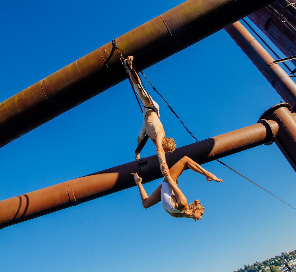 Two acrobats performing aerial routine on metal structure