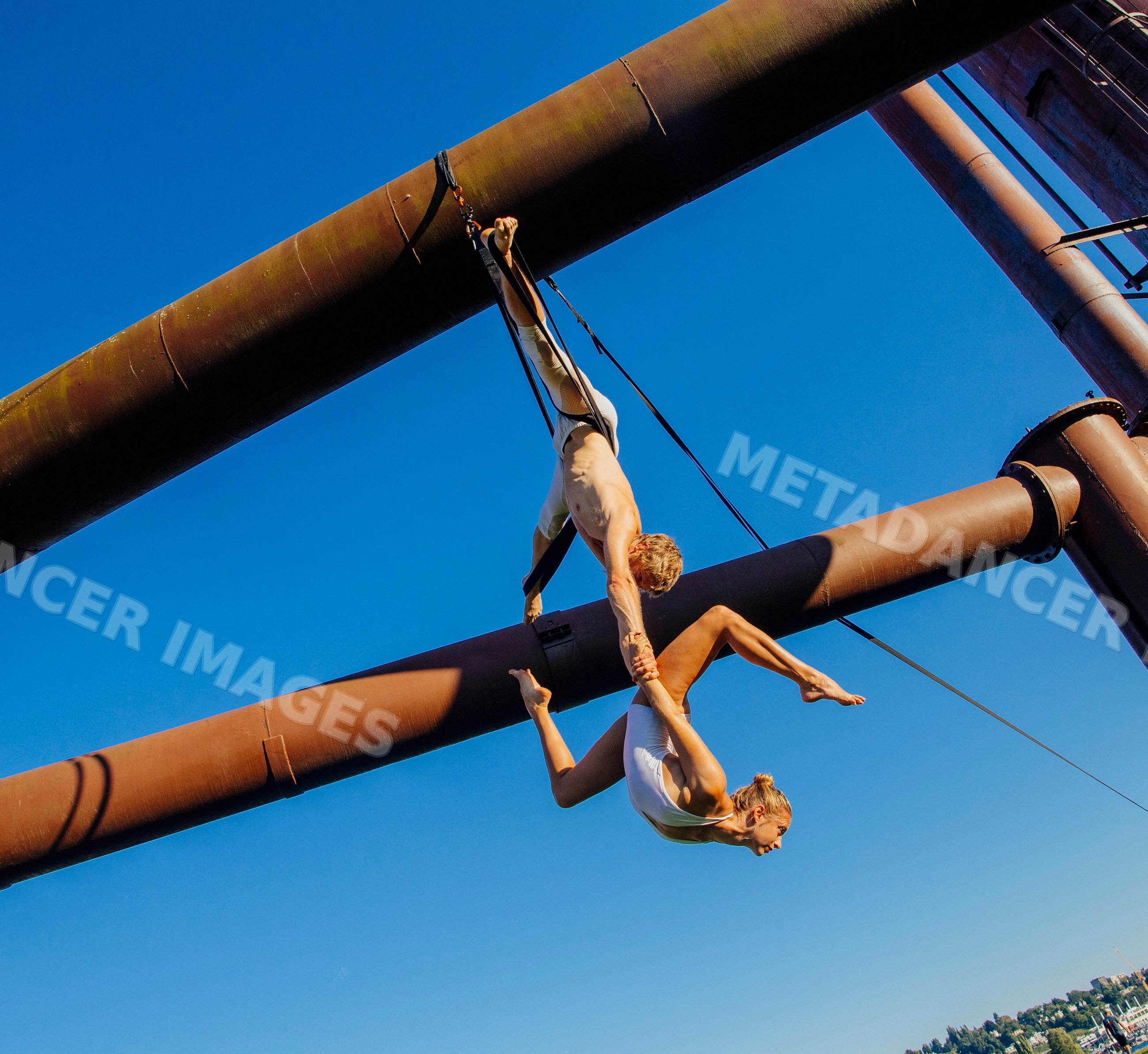 Two acrobats performing aerial routine on metal structure