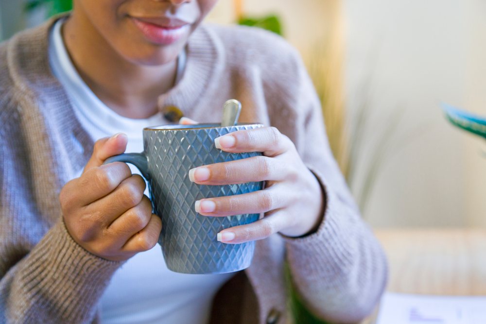 African American woman a mug of hot beverage indoors at home