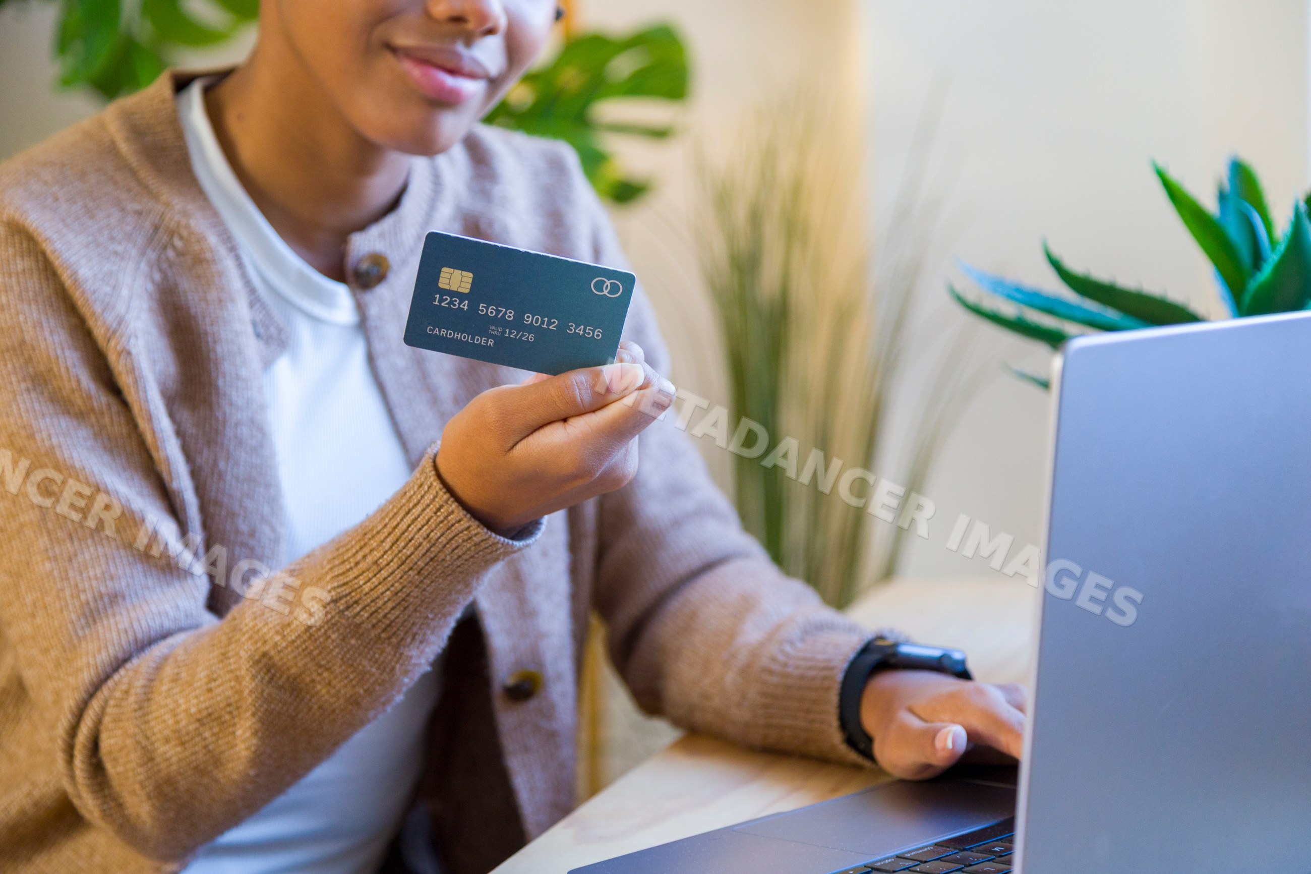African American woman holding credit card using laptop in home office