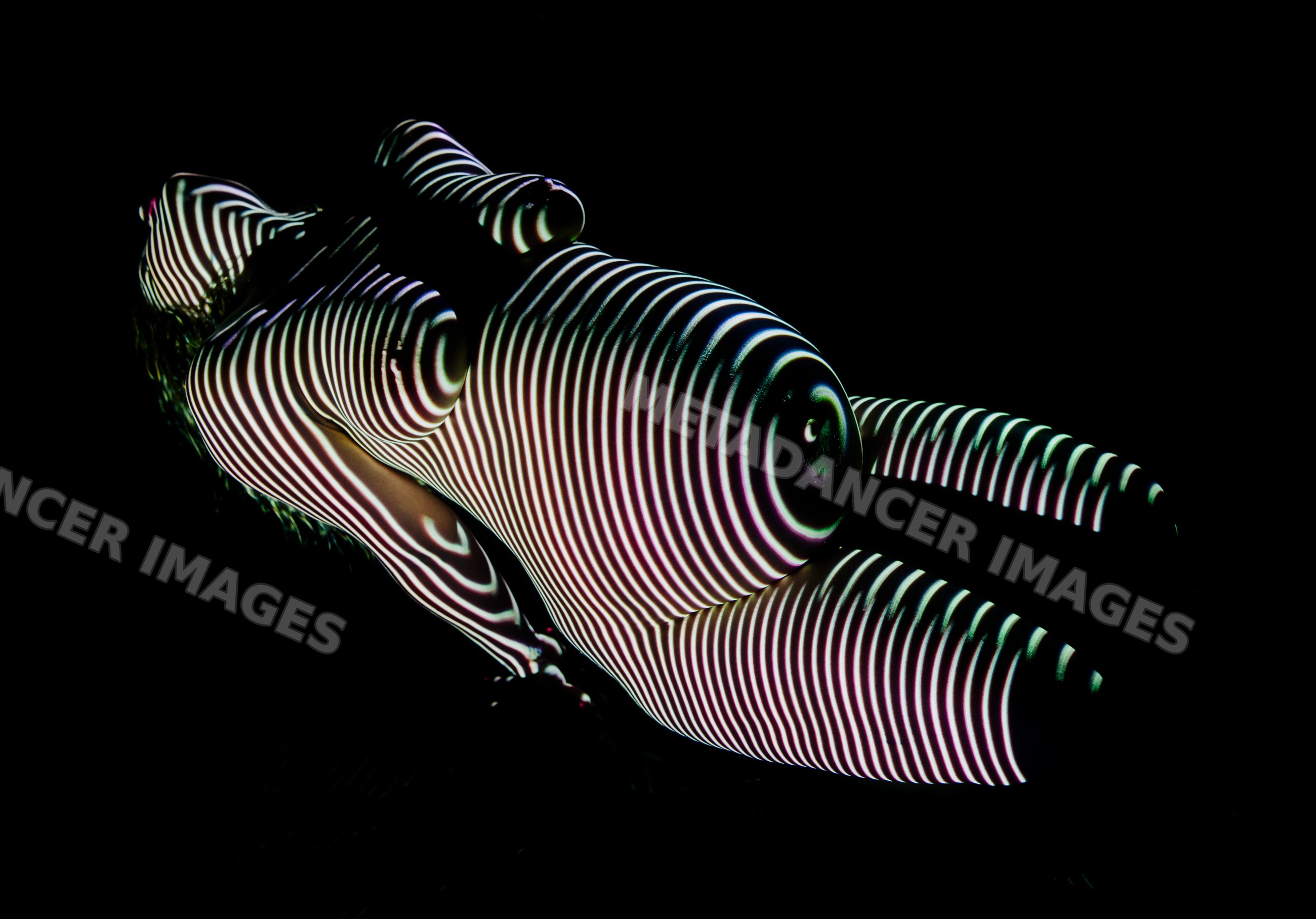 Nude white woman with striped light projection on body against black