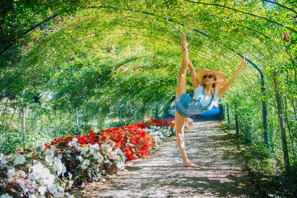 White woman stretching in flower tunnel in Tacoma garden