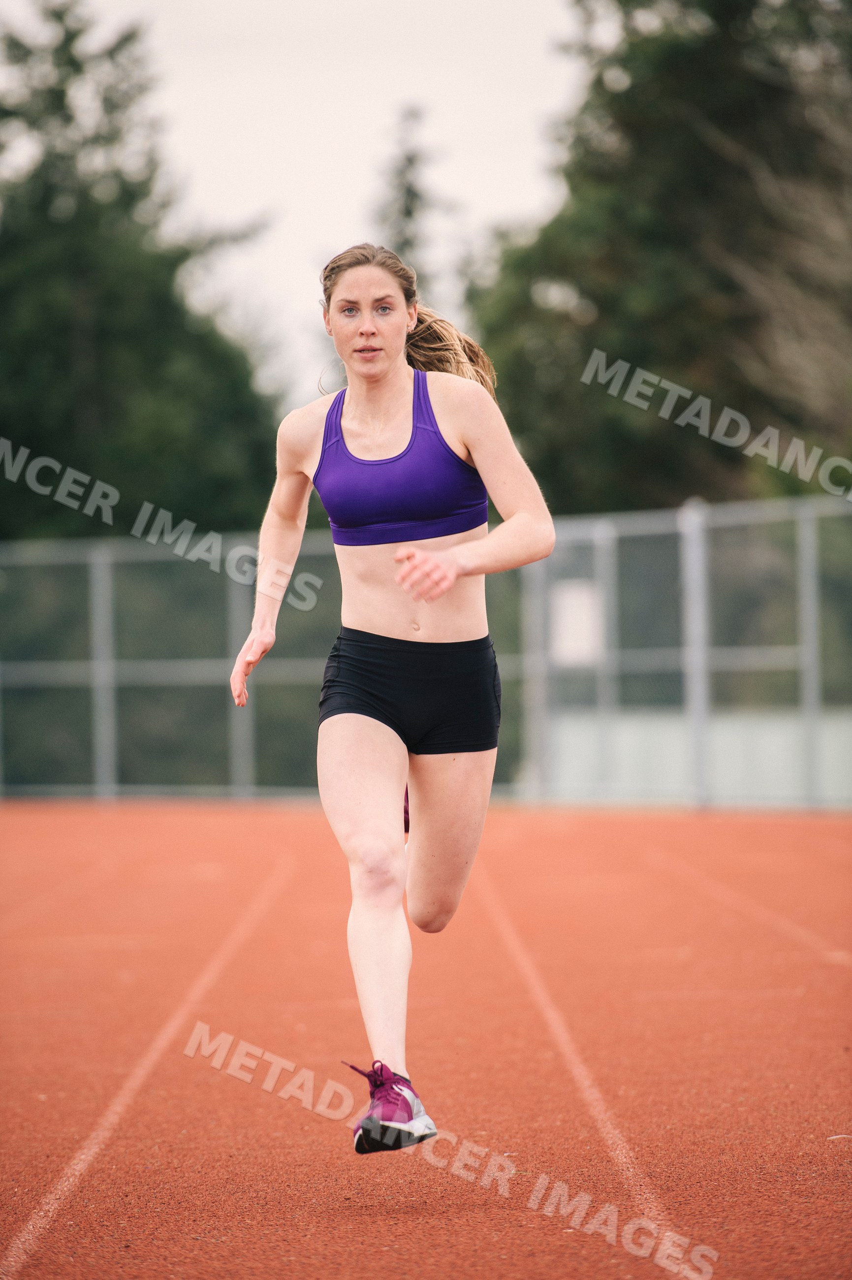 White woman running on outdoor track during athletic training