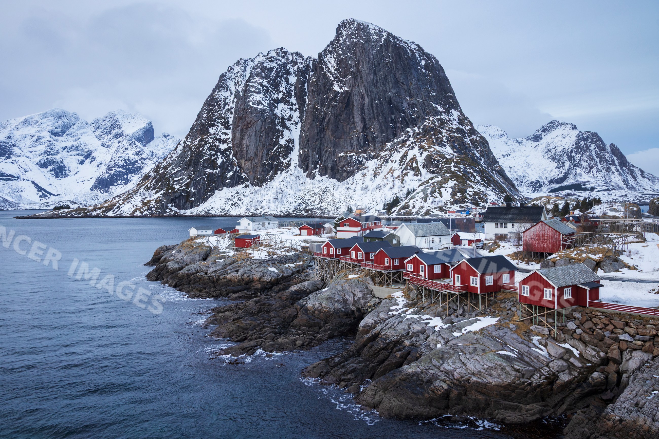 Red houses on rocky coastline by mountain in Hamnoy, Lofoten, Norway