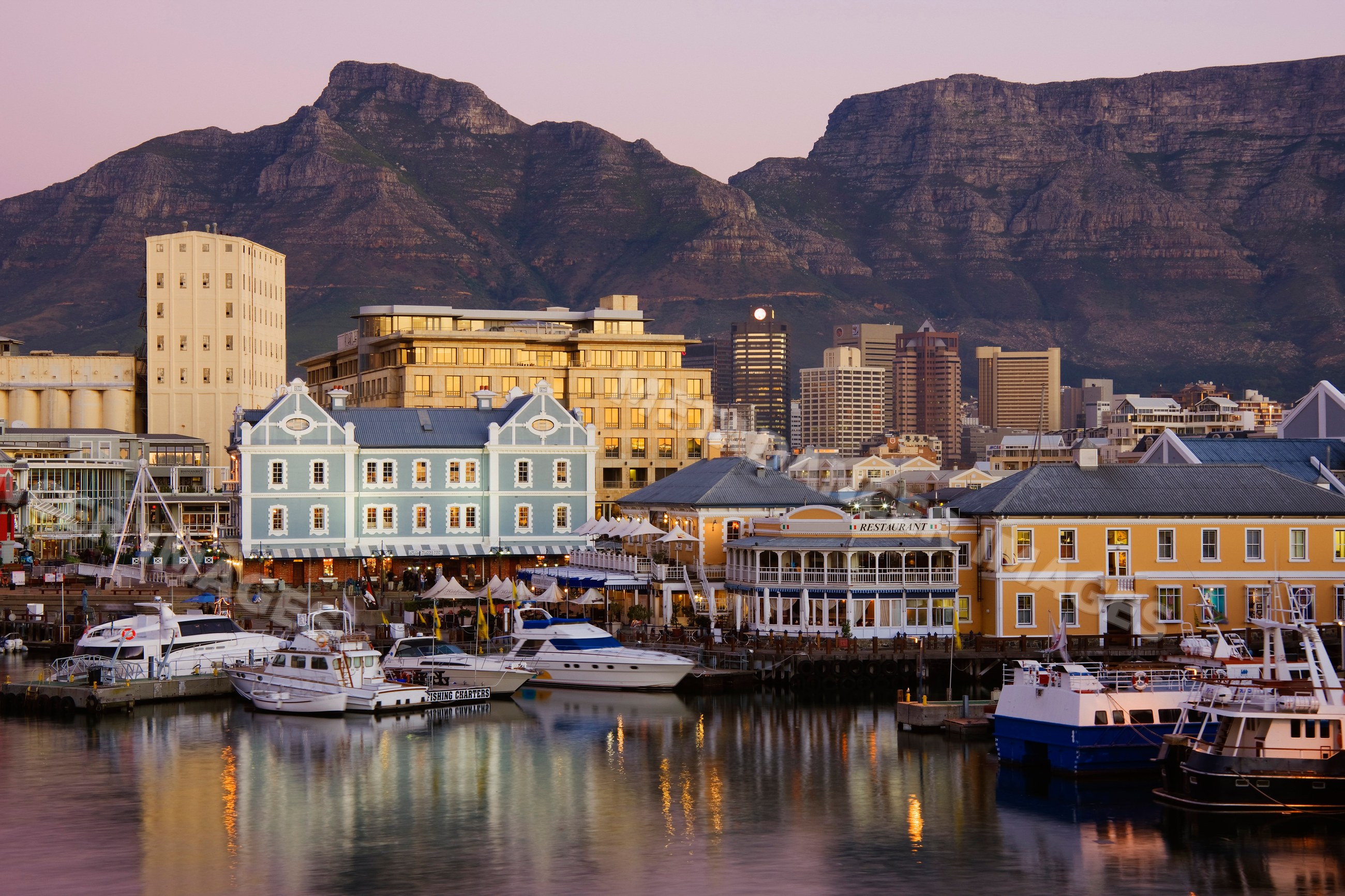 Harbor waterfront with boats and buildings at sunset