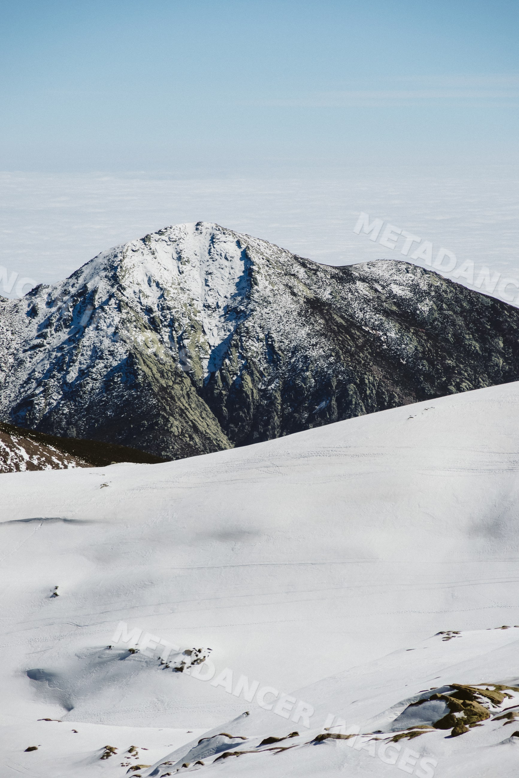 Snow-covered mountain ridge under blue sky