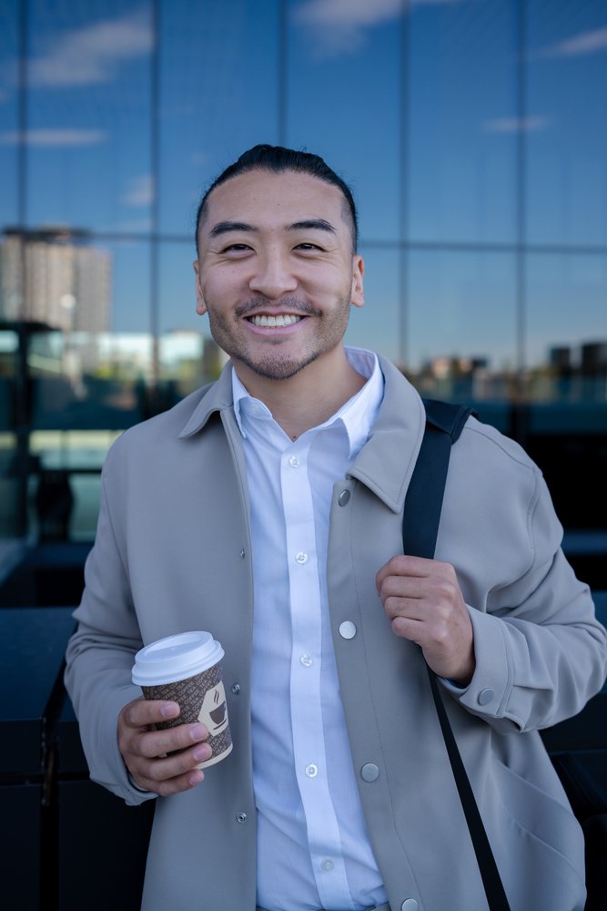 Man smiling with coffee cup outdoors in urban setting