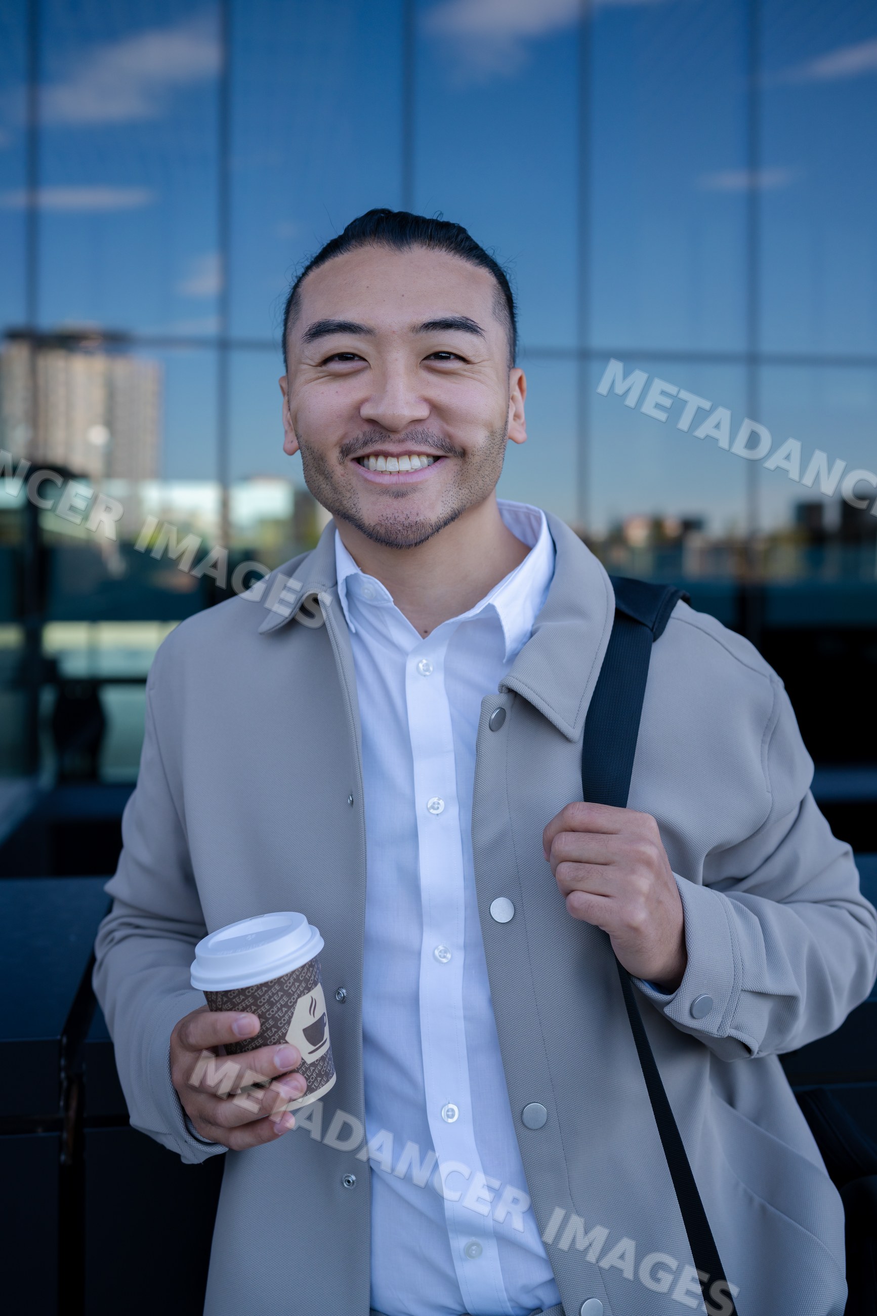 Man smiling with coffee cup outdoors in urban setting