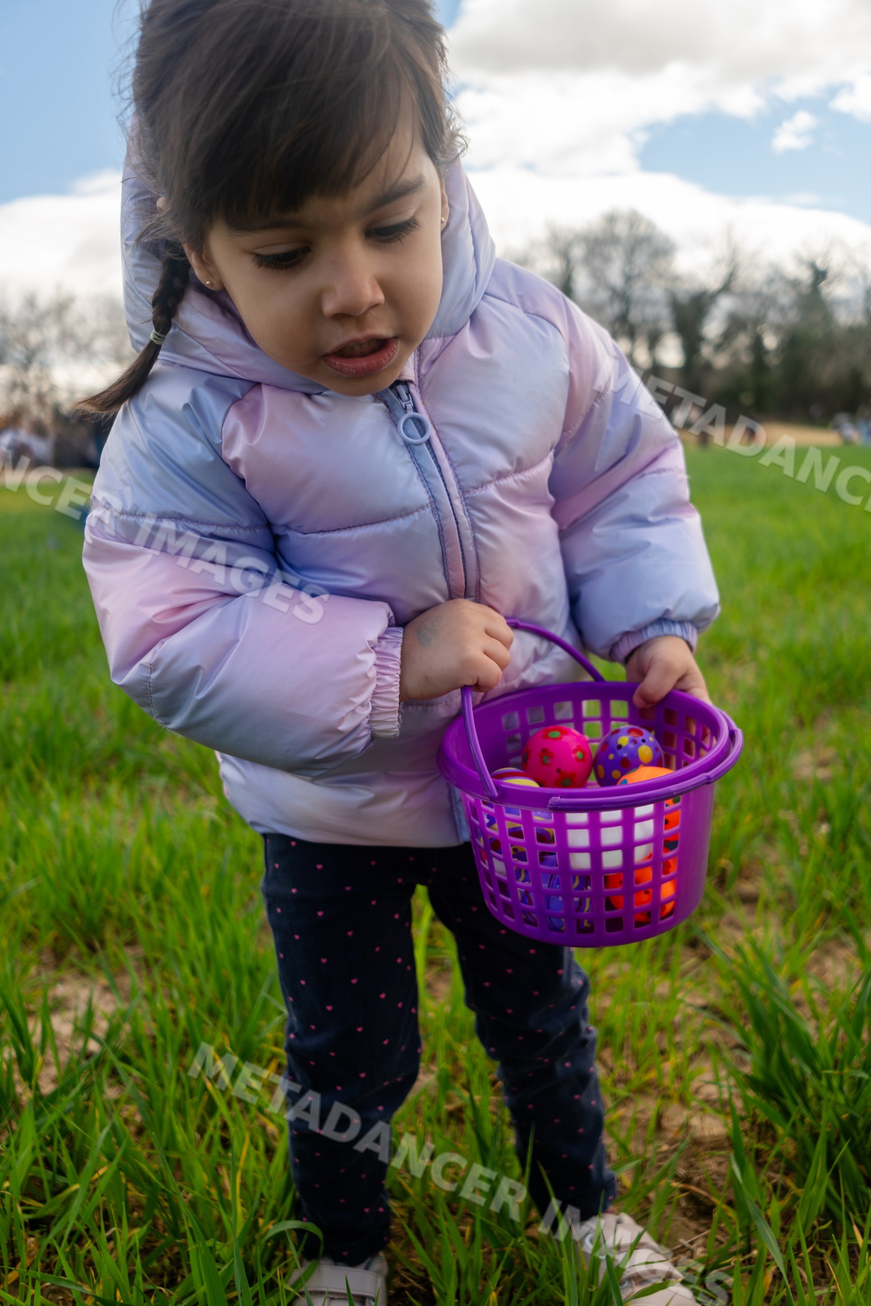 A young white girl holding a purple basket with colorful balls