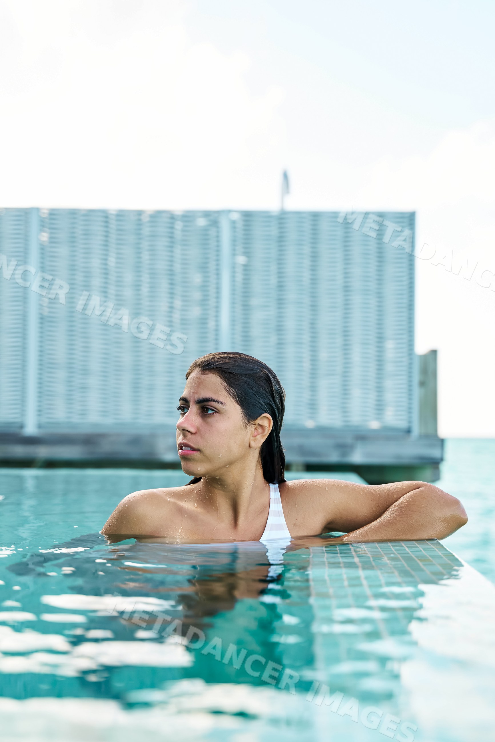 A white woman relaxes by the edge of a swimming pool