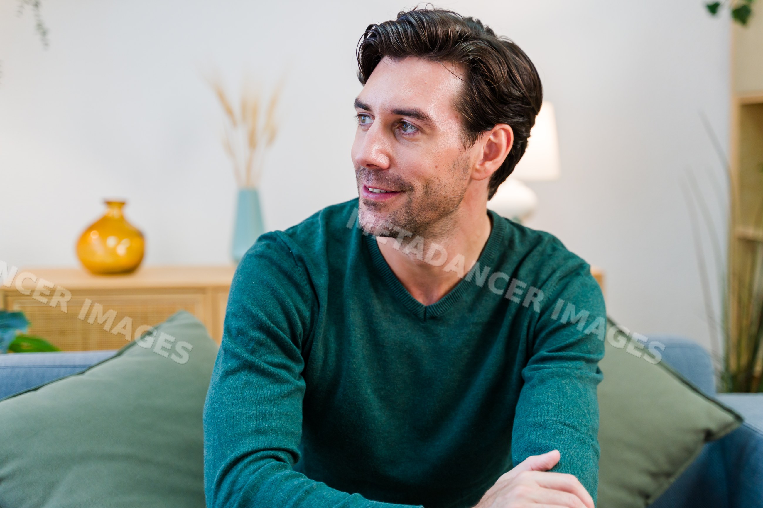 White man seated on sofa looking away in modern living room