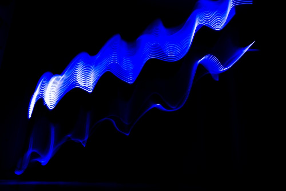 Blue light painting with wavy illuminated trails on dark background