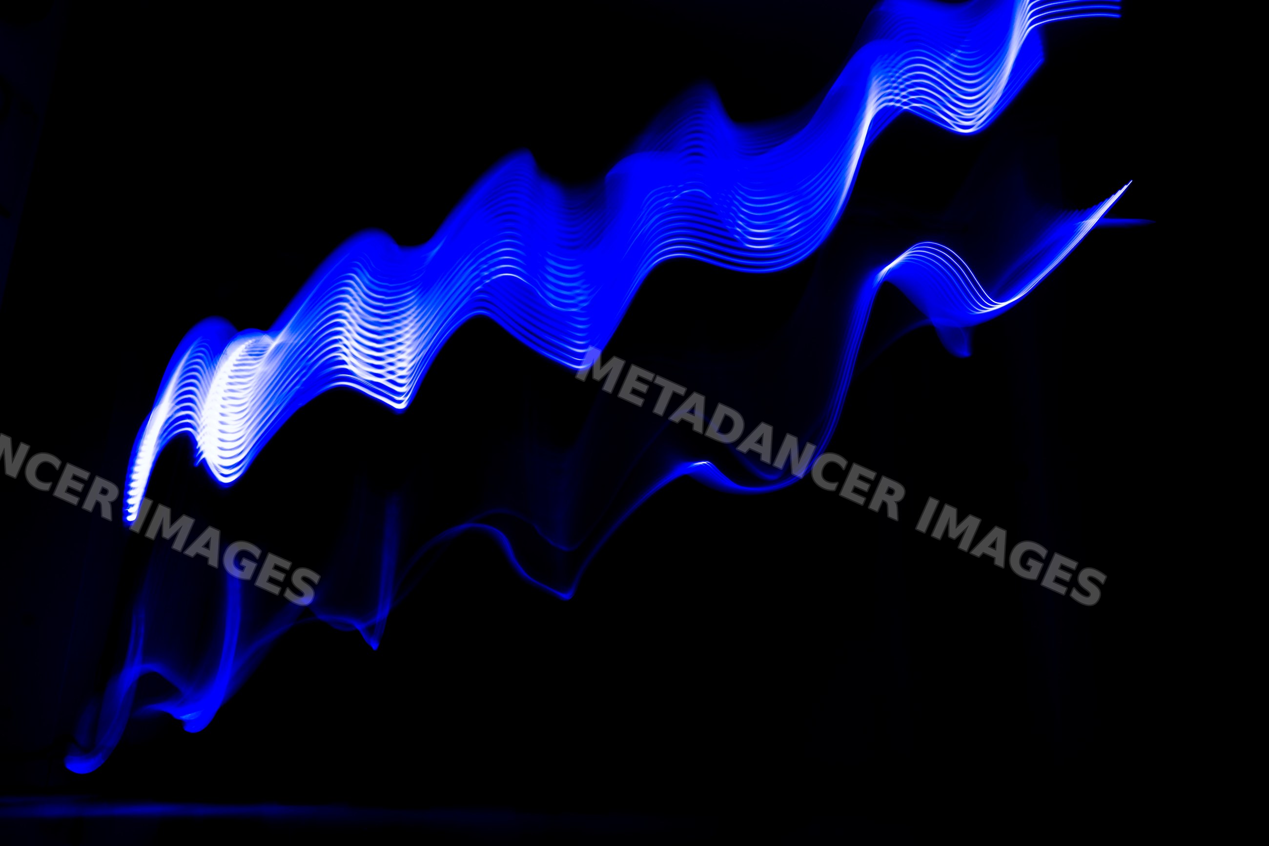 Blue light painting with wavy illuminated trails on dark background