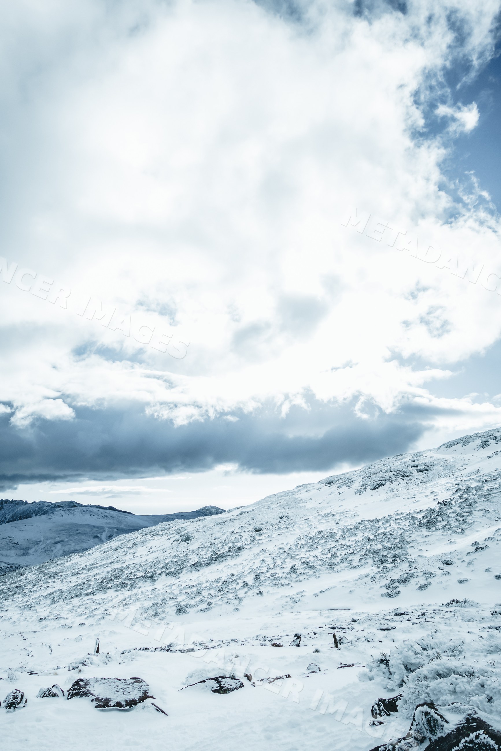 Snow-covered mountain slope under partly cloudy sky