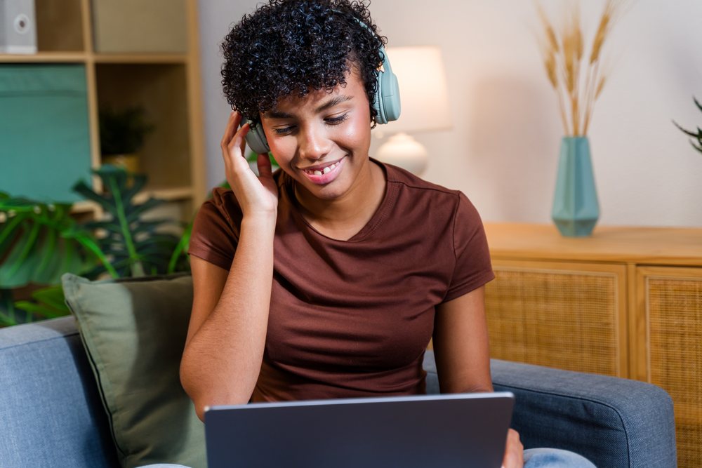 African American woman using laptop with headphones on a couch