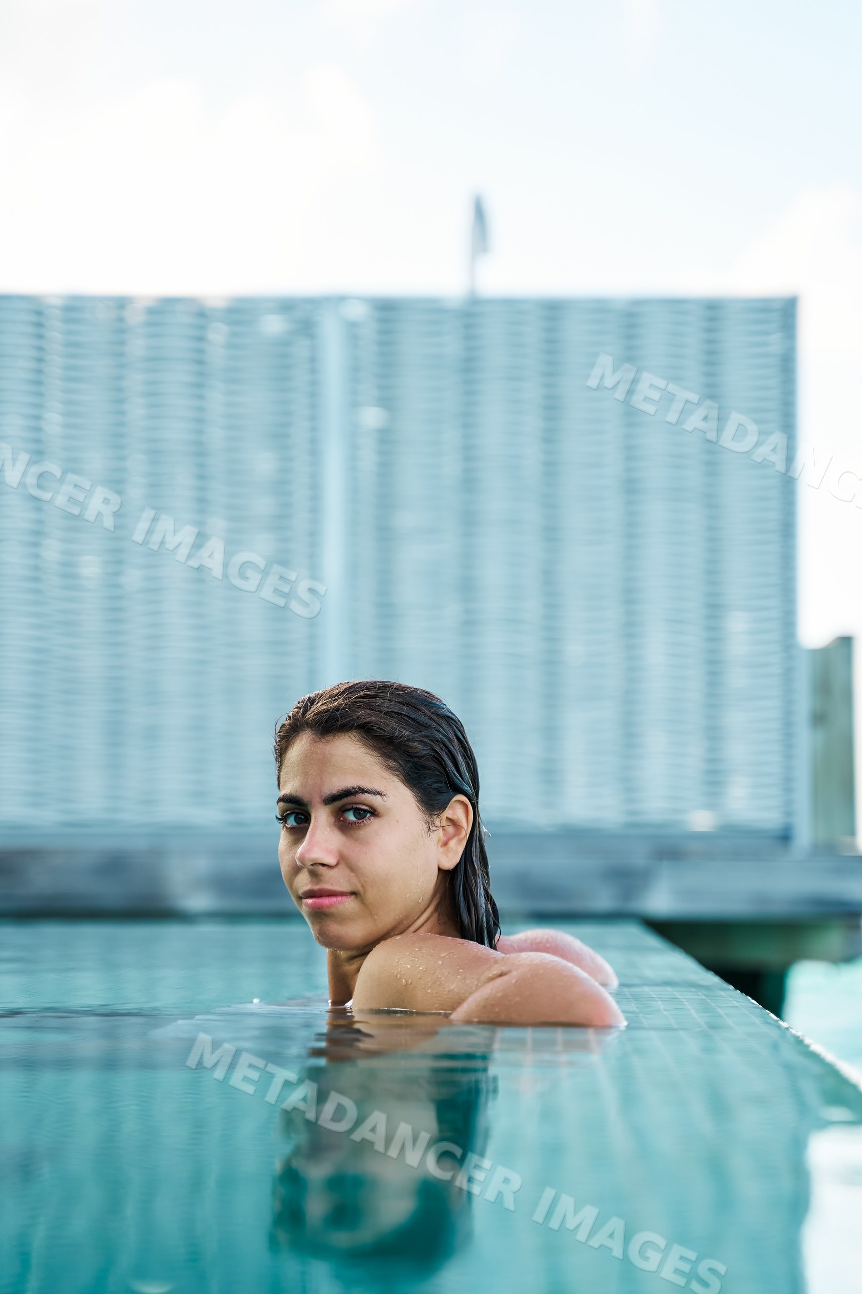 A white woman relaxes in a swimming pool by the pool edge