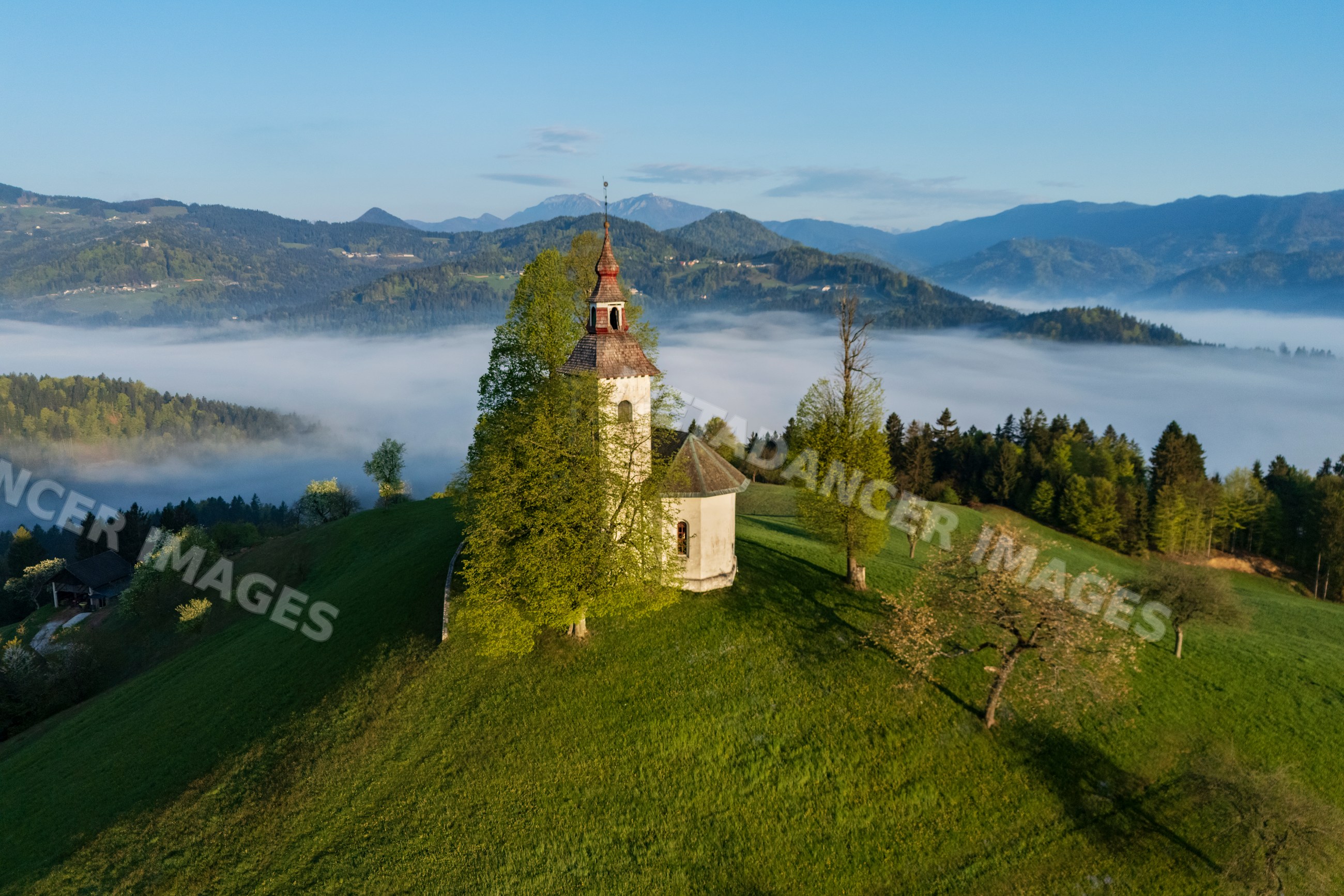 Church on hilltop at Sunrise with fog and mountains in skofje loka
