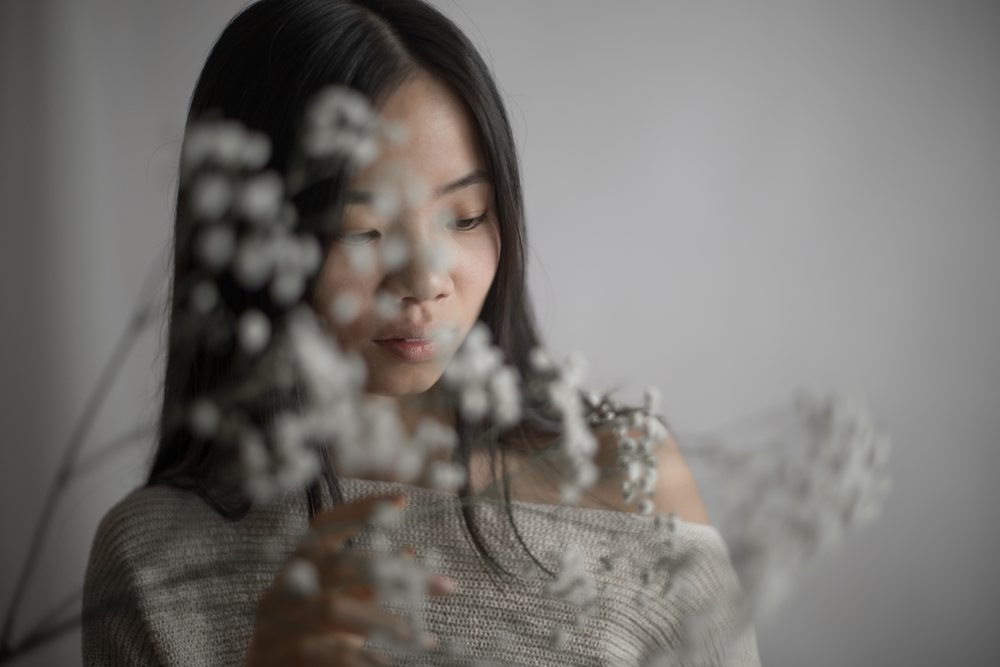 Emotional Southeast Asian woman touching delicate baby's breath