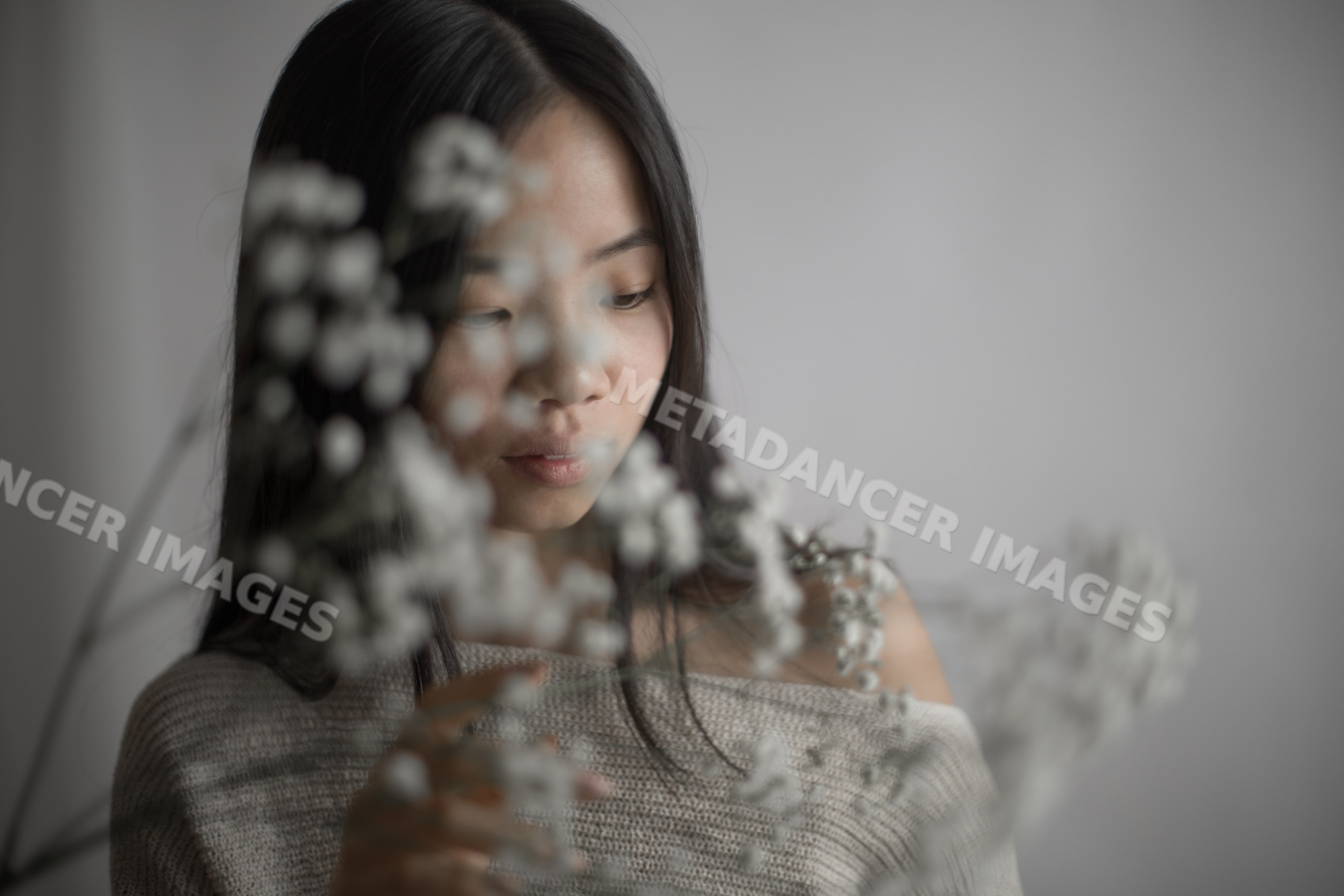 Emotional Southeast Asian woman touching delicate baby's breath