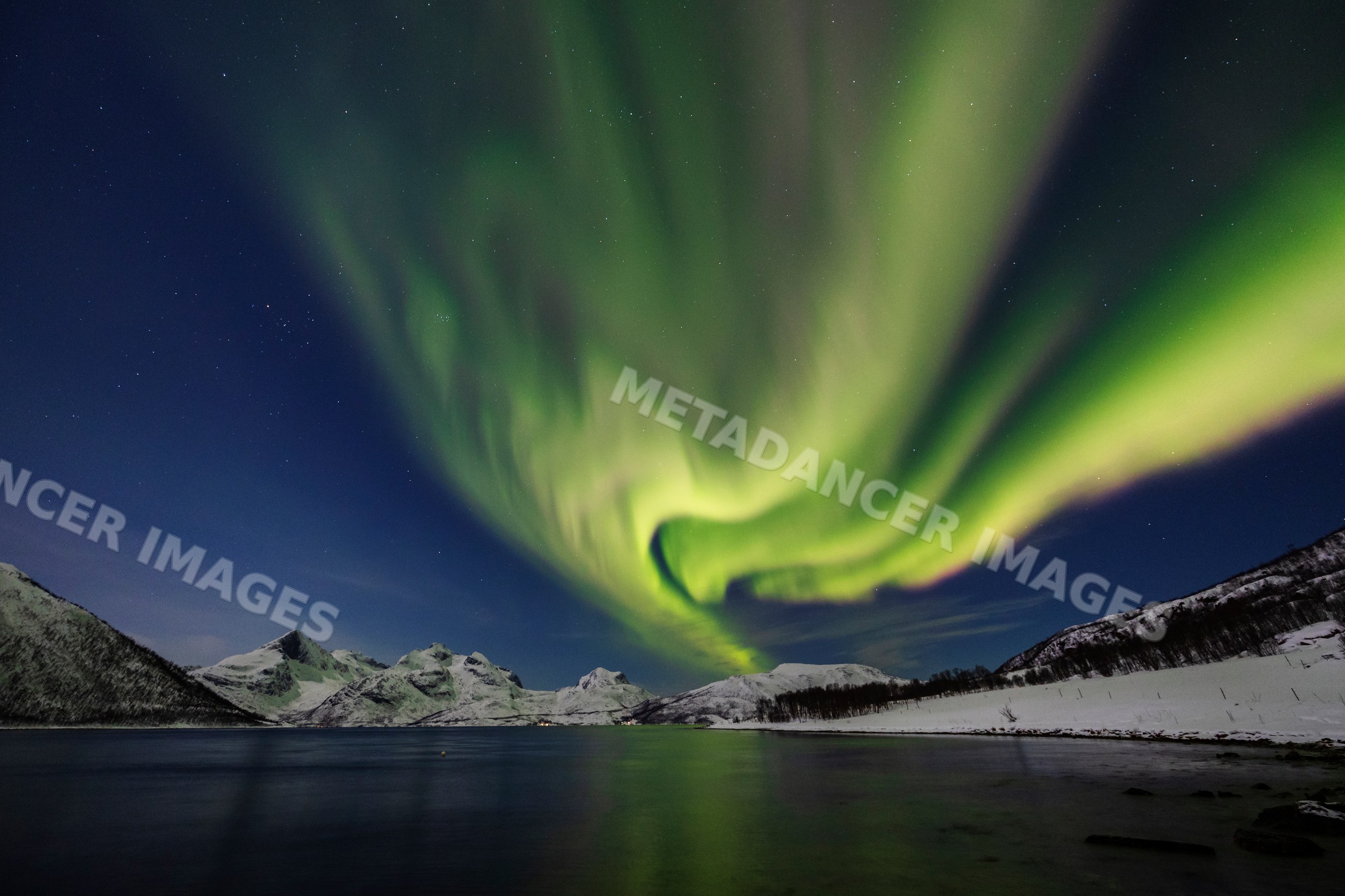 Northern Lights over snowy mountains at lyfjorden, kvaløya, Norway