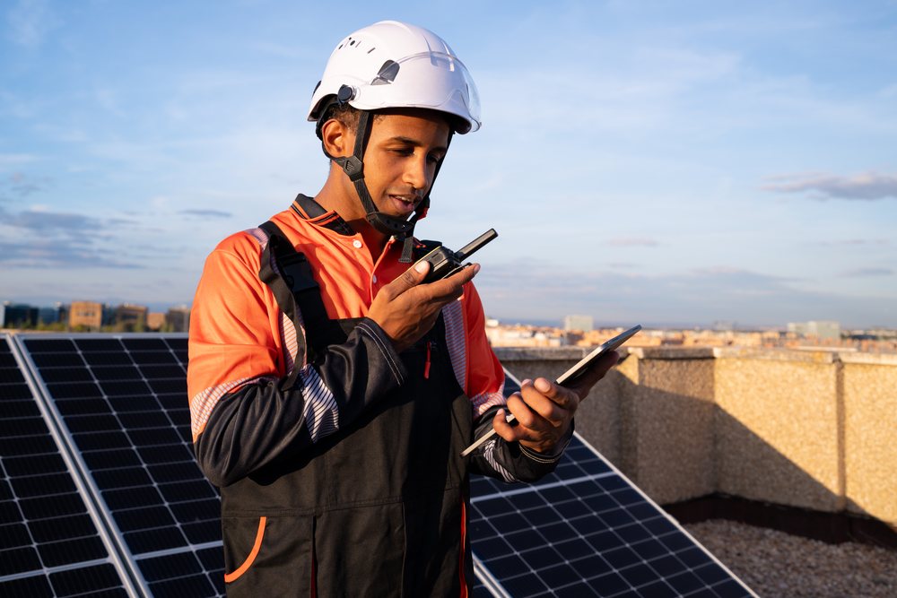 Worker inspecting solar panels on a rooftop