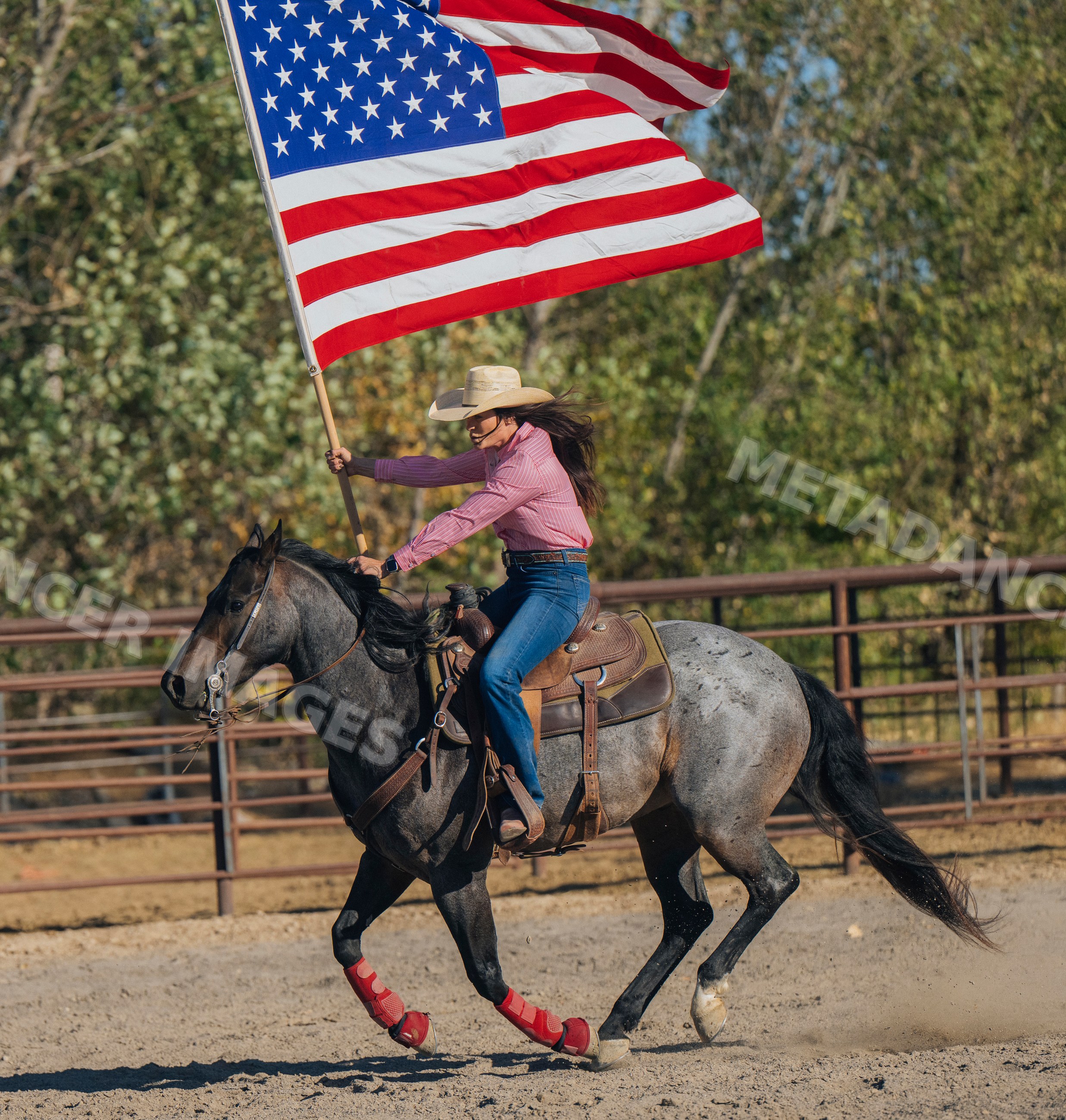Cowgirl riding horse waving american flag in rodeo arena Southwest USA