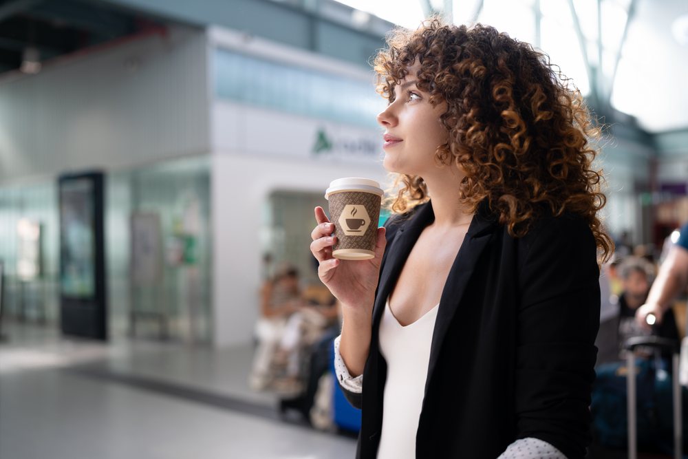 White woman holding coffee cup in indoor public waiting area