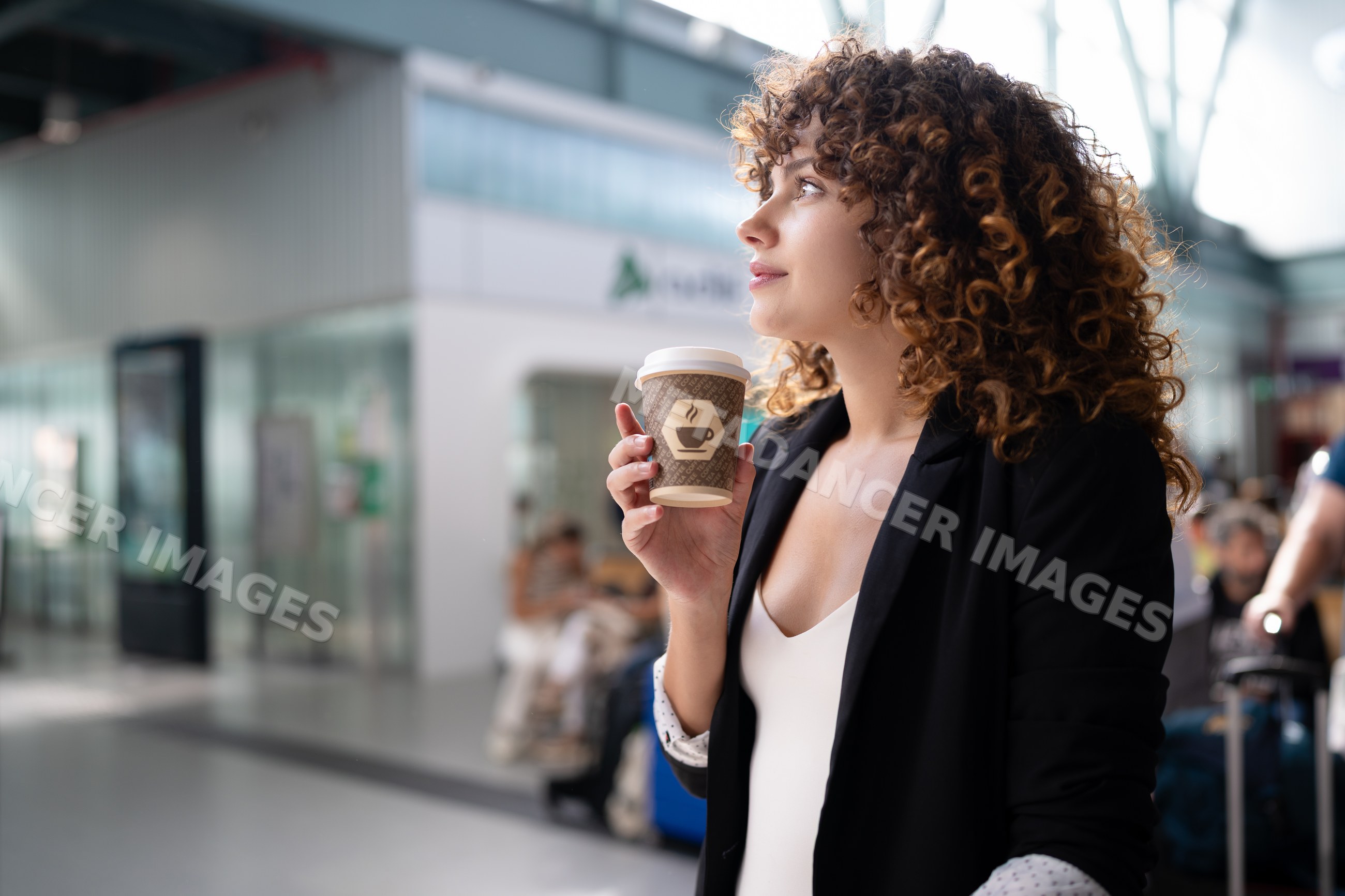 White woman holding coffee cup in indoor public waiting area