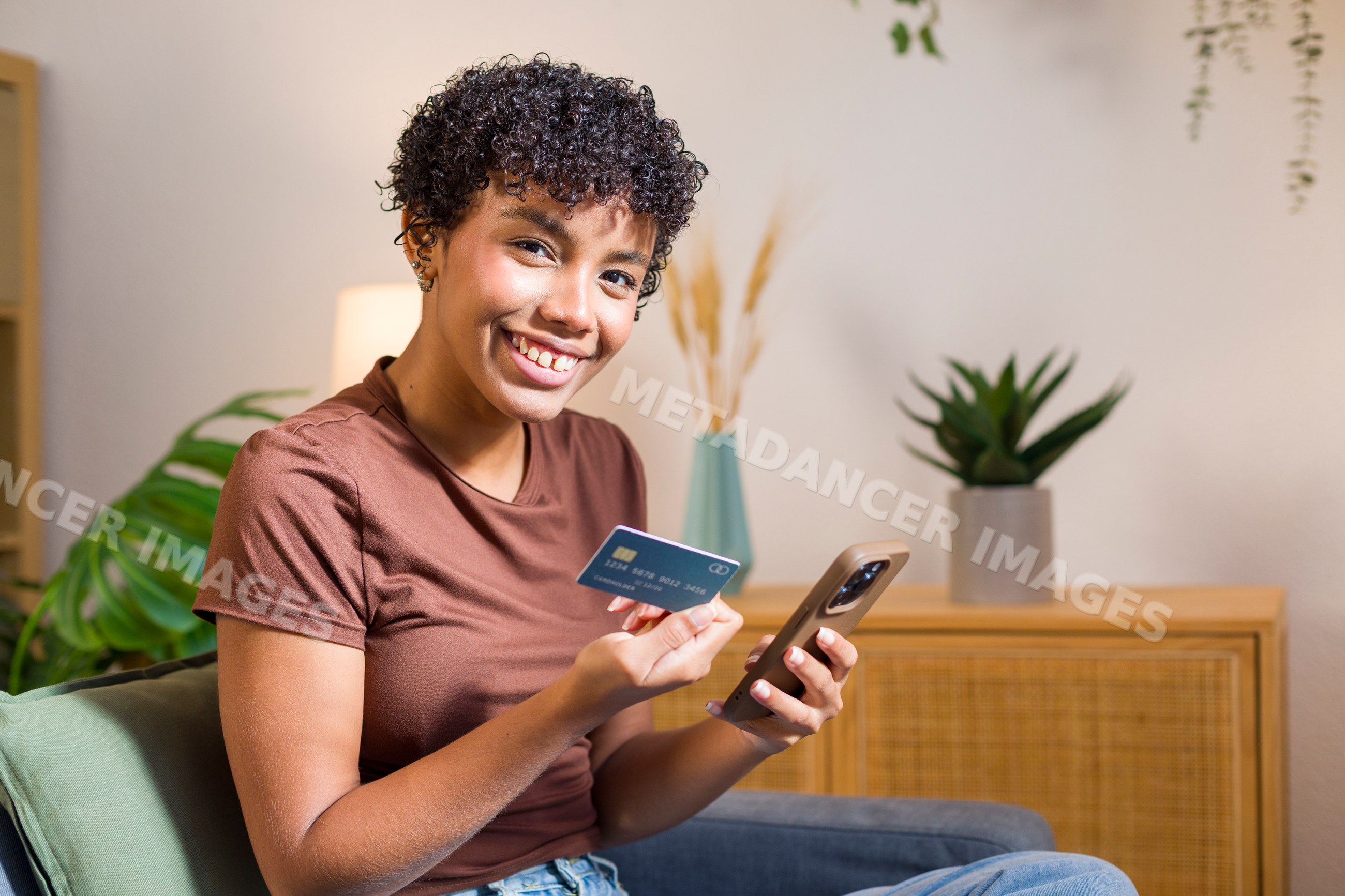 Young African American woman holding credit card and using smartphone