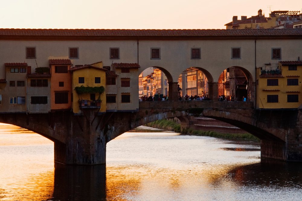 Ponte vecchio stone bridge over arno river at sunset, italy
