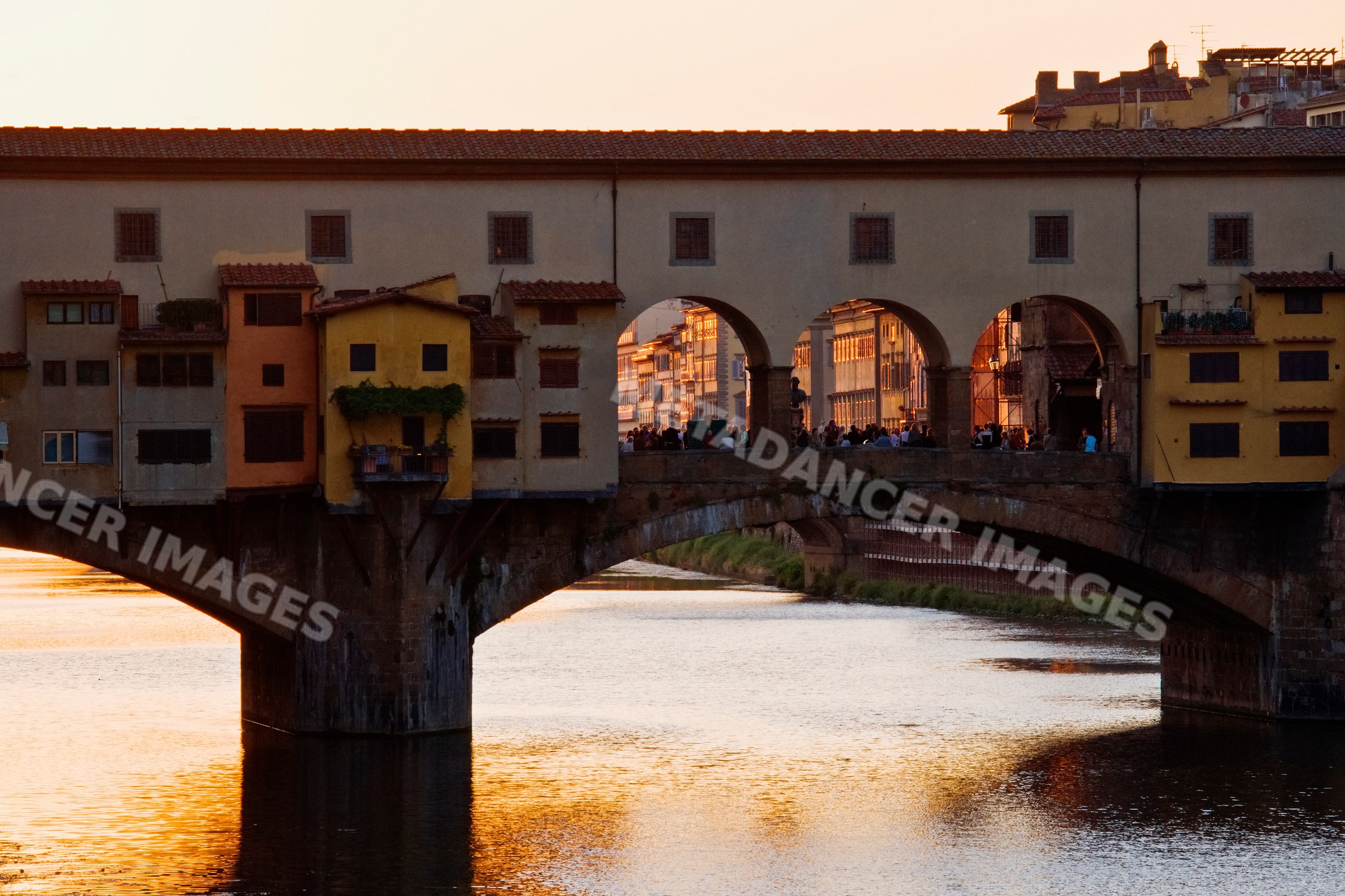 Ponte vecchio stone bridge over arno river at sunset, italy