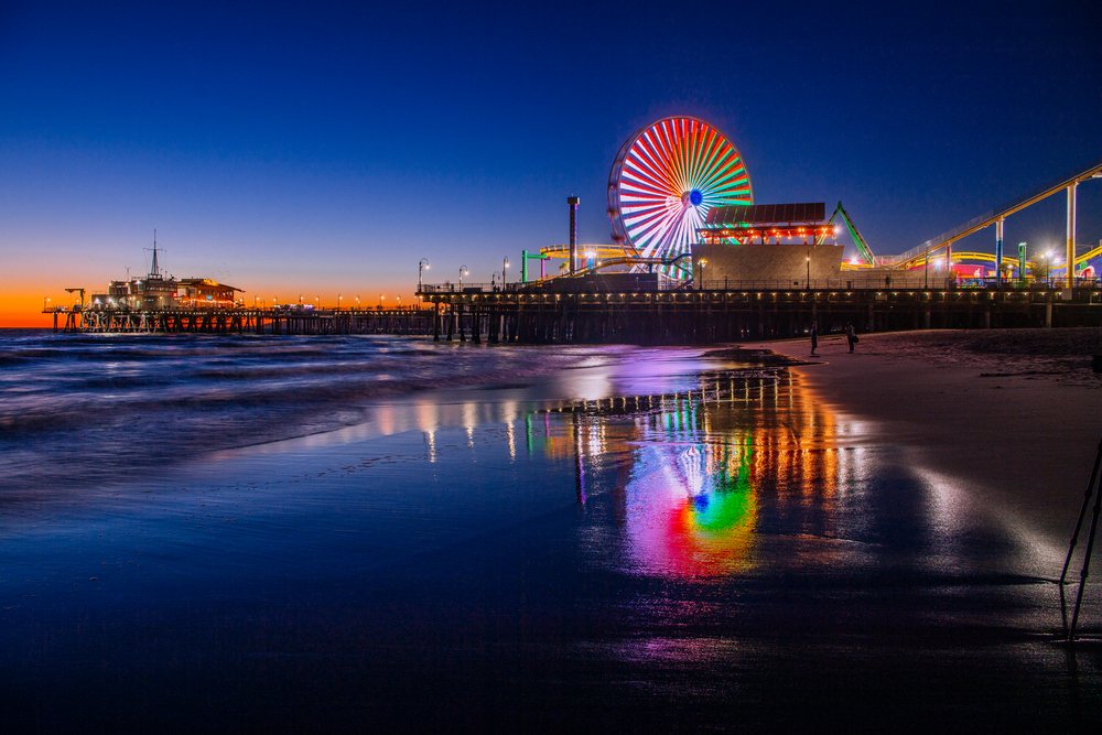Santa Monica pier ferris wheel lights reflecting on beach at sunset