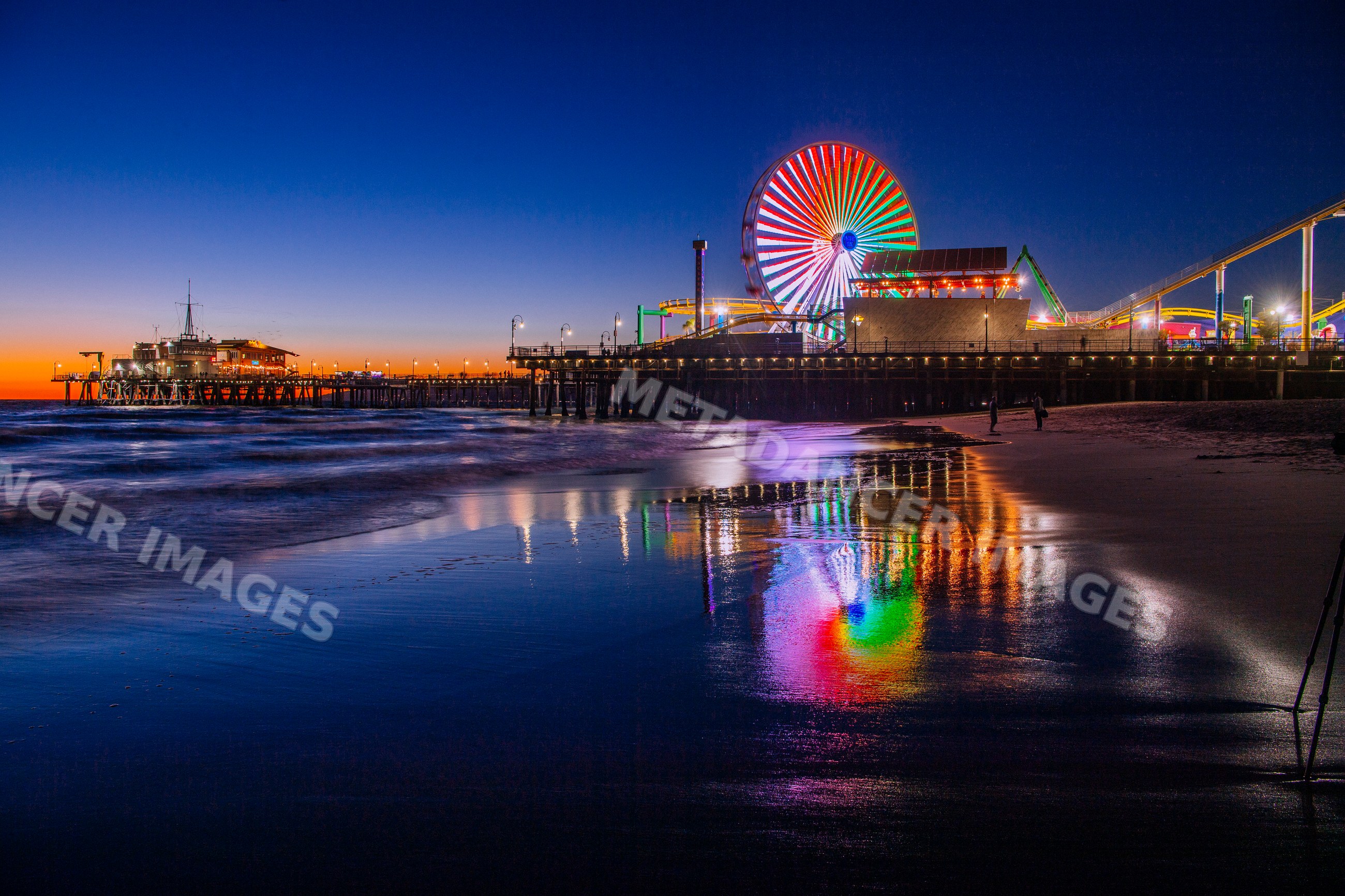 Santa Monica pier ferris wheel lights reflecting on beach at sunset