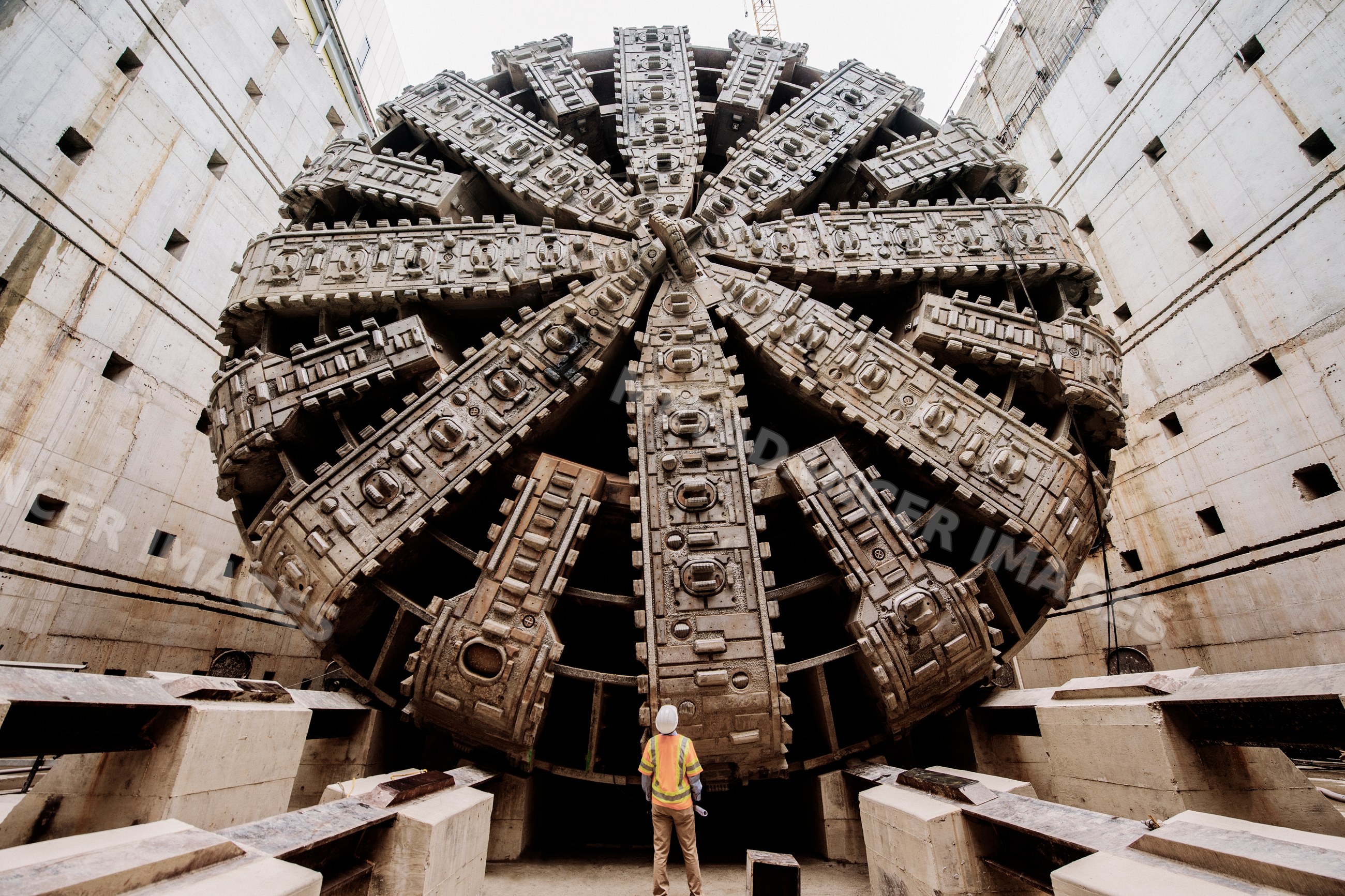 A white worker inspects a massive tunnel boring machine