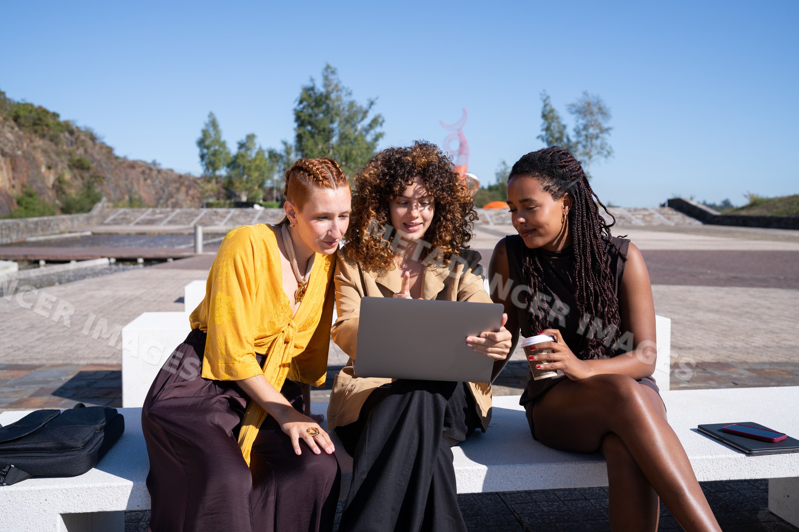 Three African American and white women collaborating on a laptop