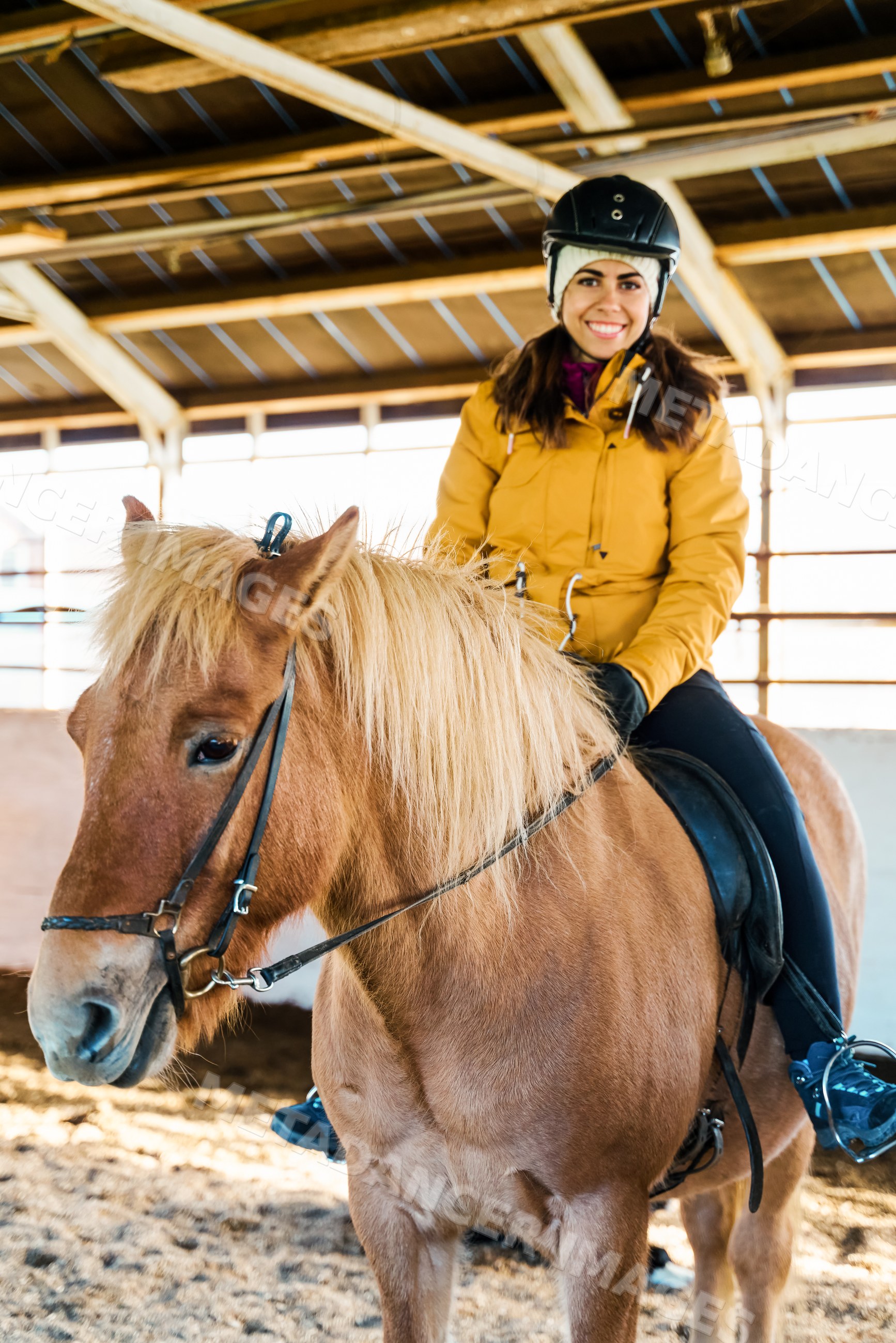 A white woman rides a horse inside an indoor arena