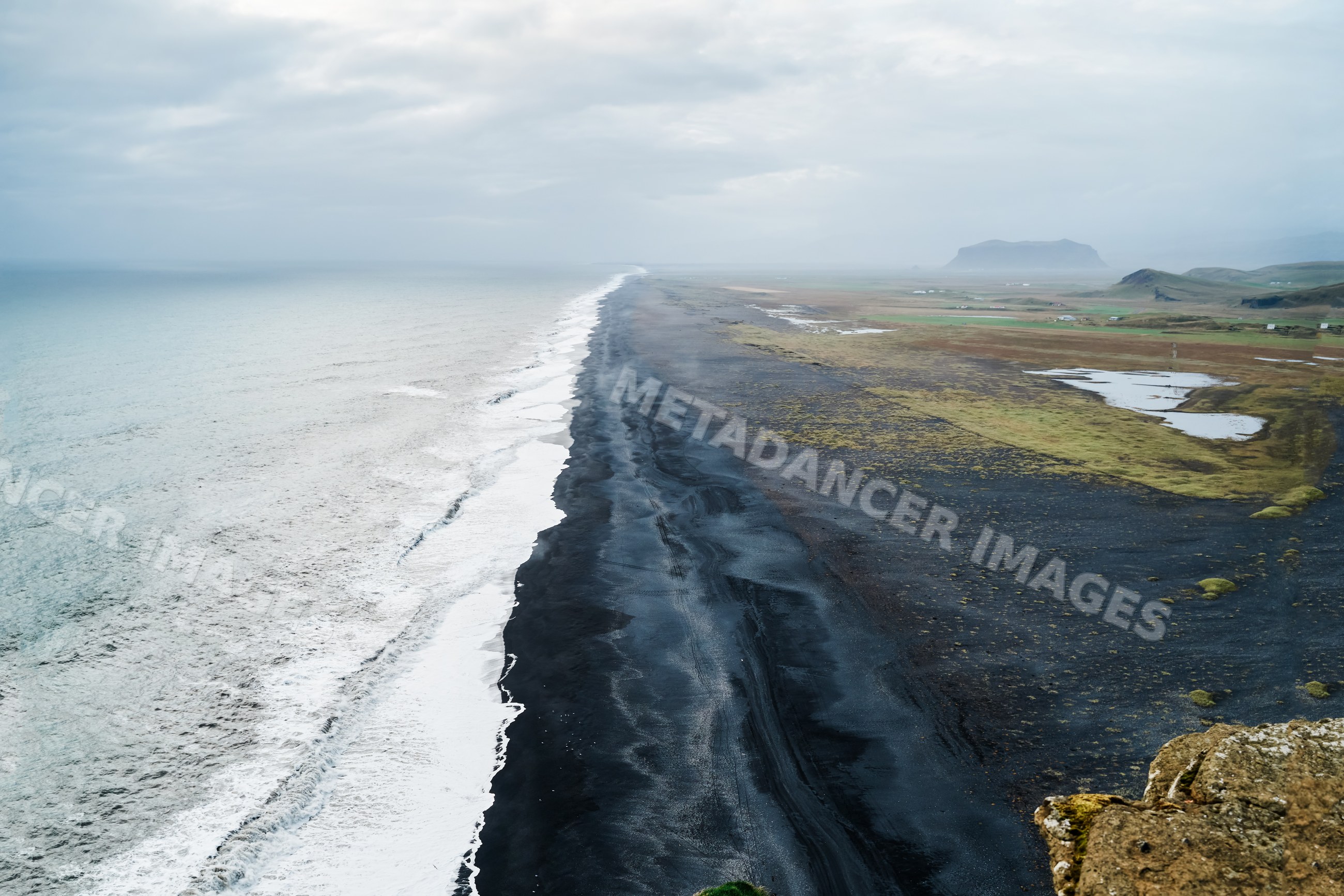 Aerial view of a black sand beach and ocean waves along an Iceland