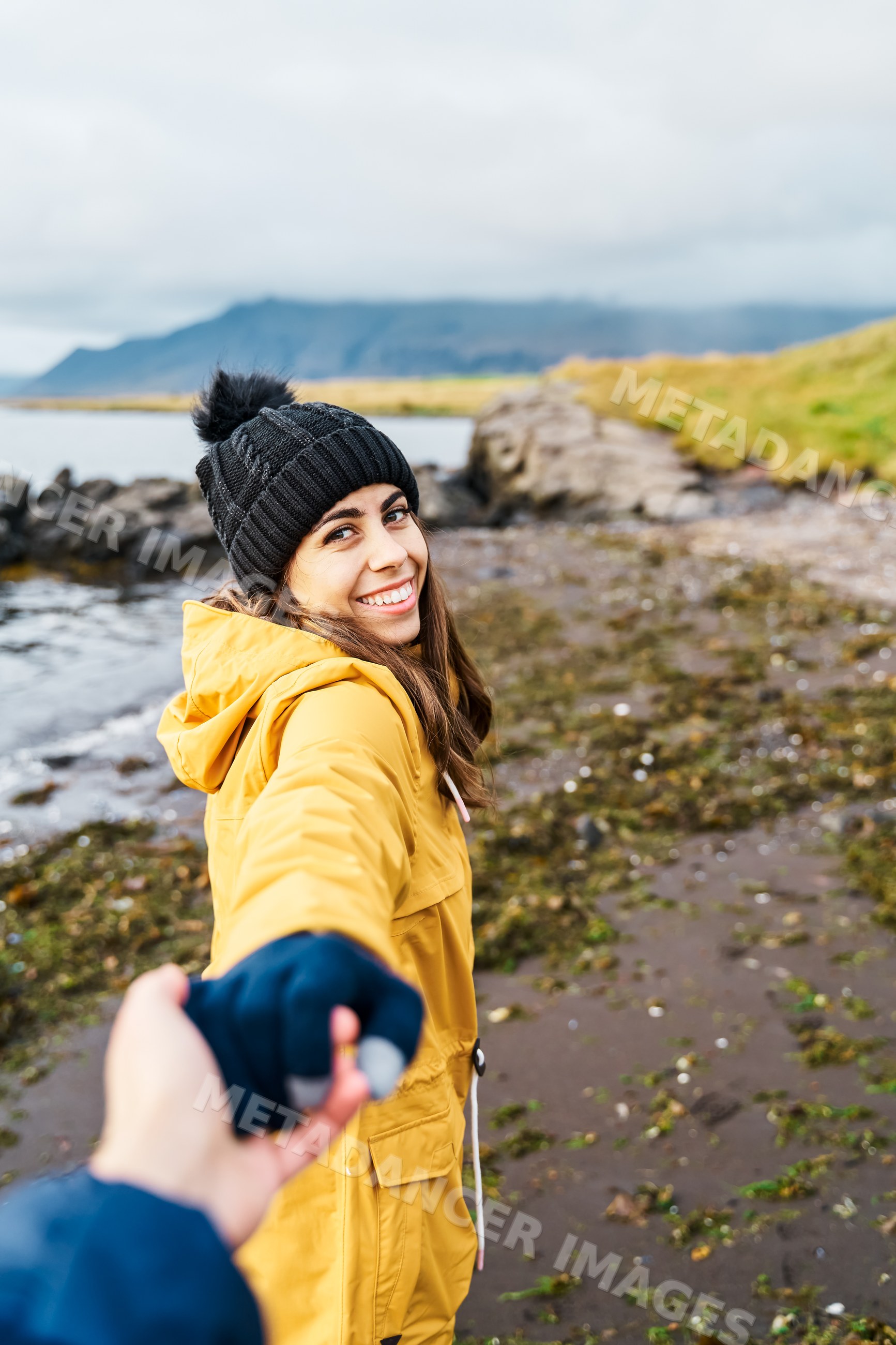White Woman holding hand walking along the rocky coastal shore
