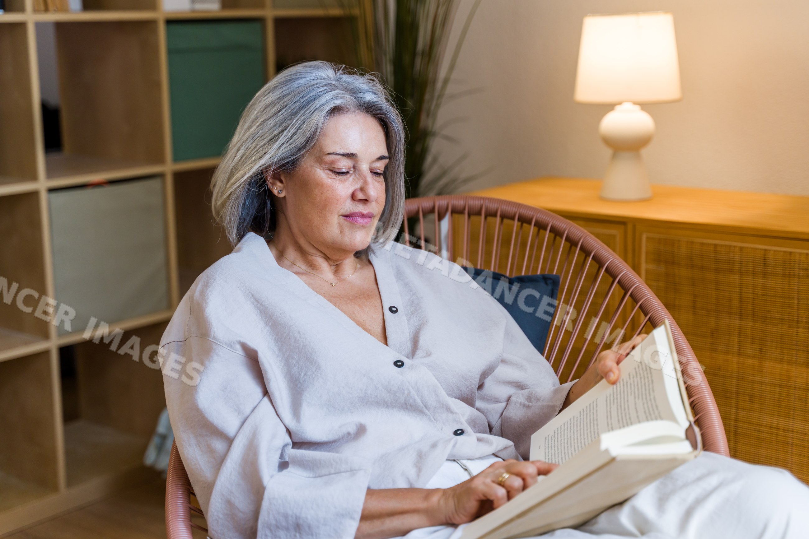 White woman reading book relaxing in chair indoors