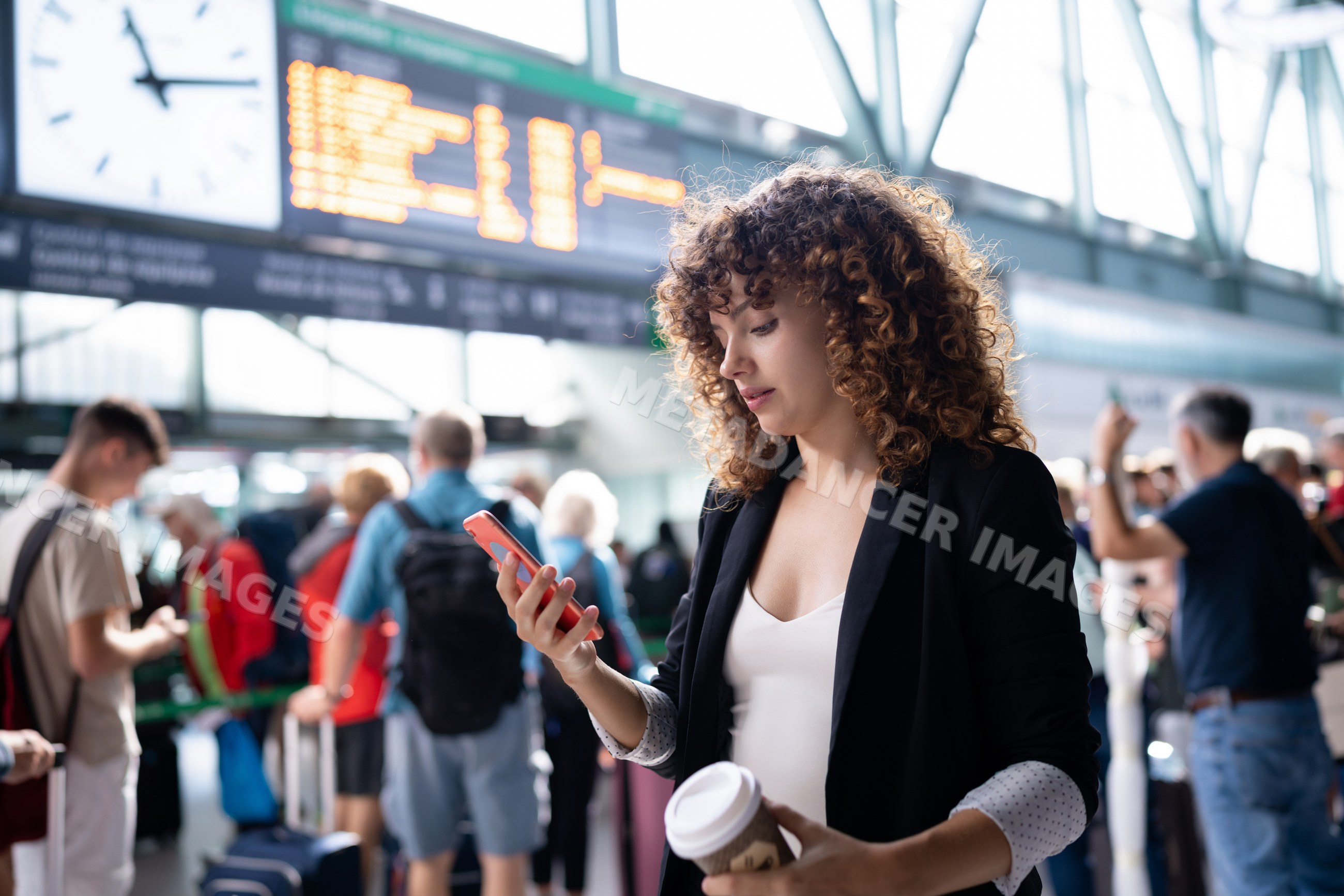 White woman checking phone while waiting queue